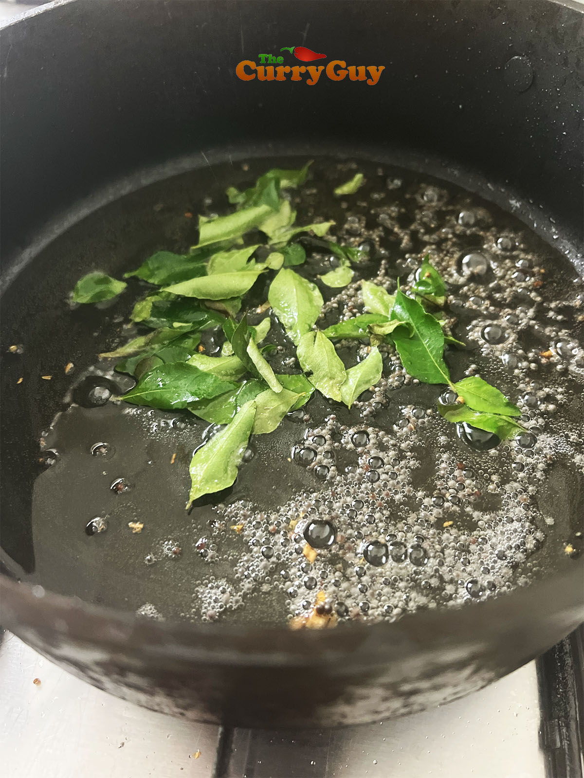 Frying mustard seeds and curry leaves in oil.