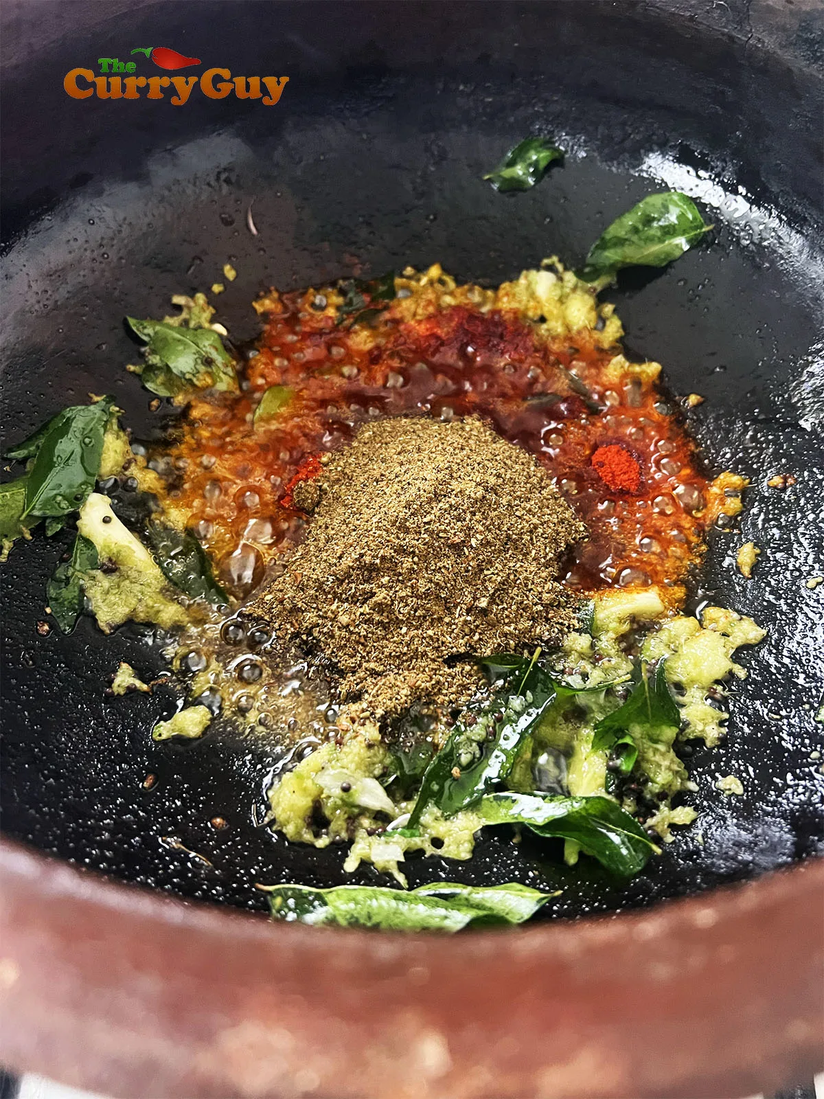 Adding ground spice blend and also chilli powder to the oil.