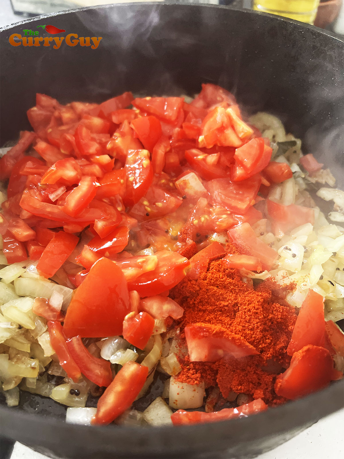 Adding chopped tomatoes to the pan