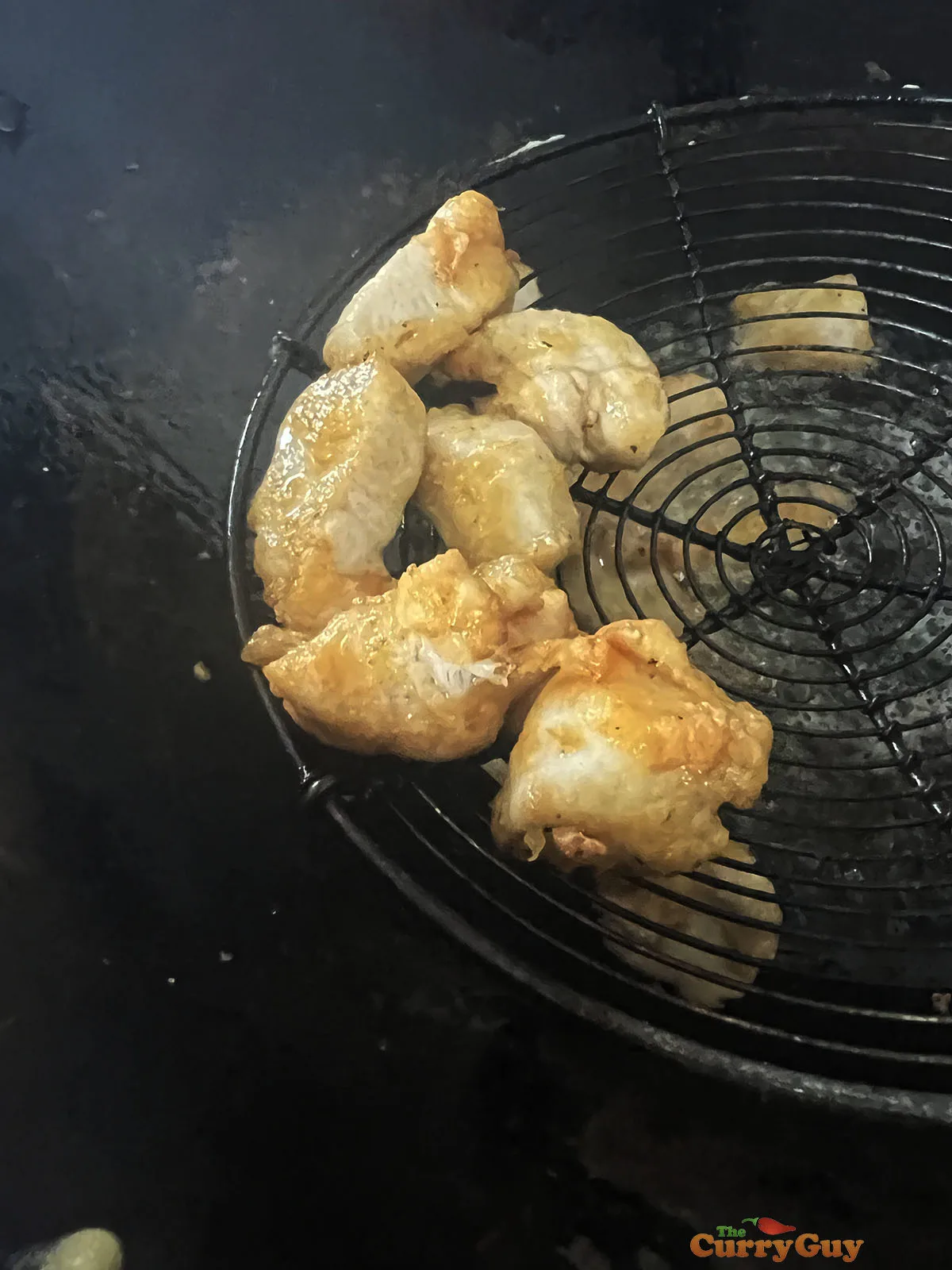 Transferring the cooked chicken out of the oil.