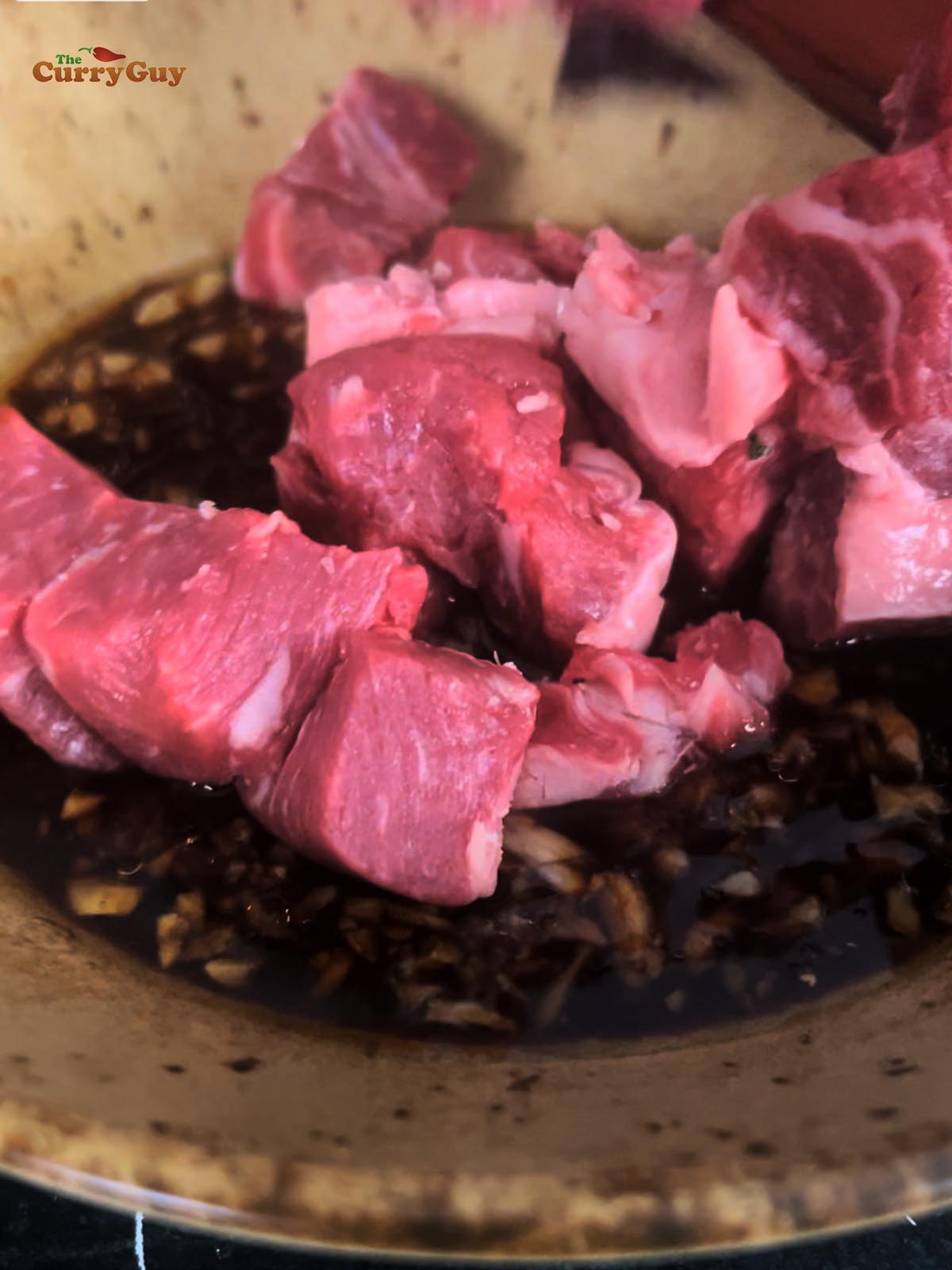Adding cubed beef to the marinade.