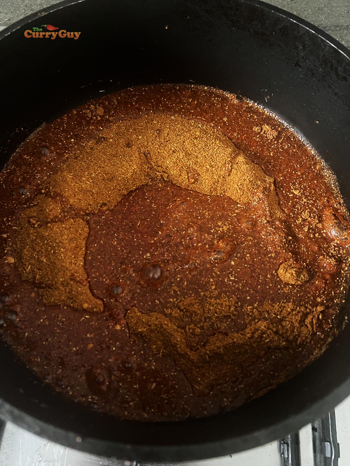Adding water to tandoori masala powder in a pan.