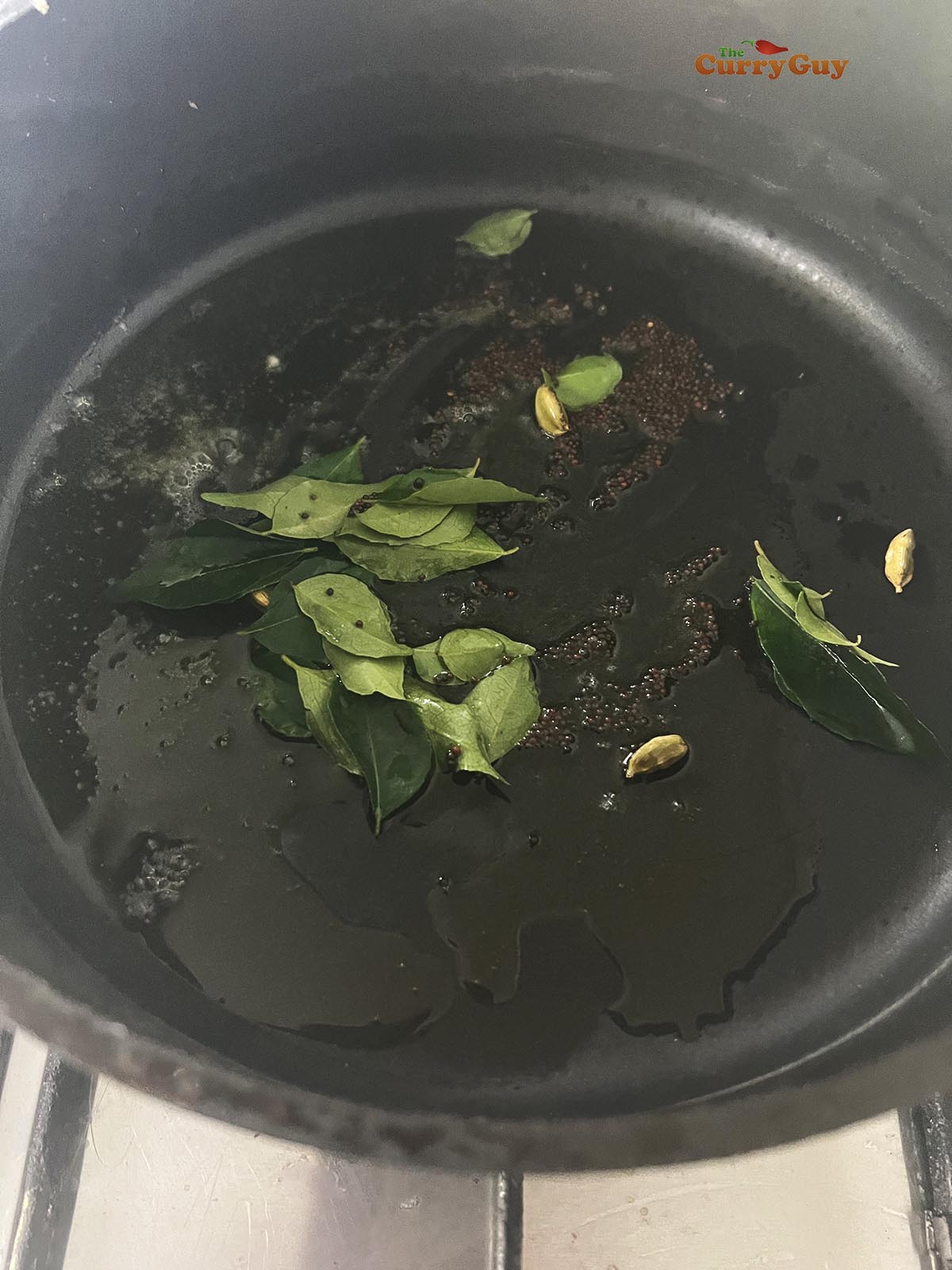 Infusing the flavours of mustard seeds, curry leaves and cardamom pods in hot ghee.