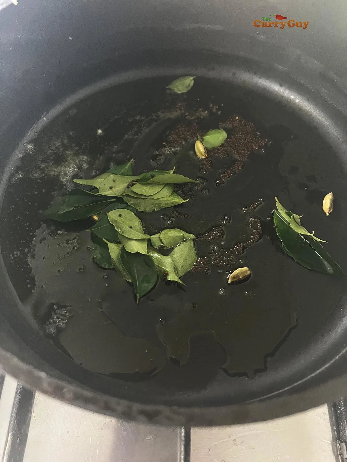 Infusing the flavours of mustard seeds, curry leaves and cardamom pods in hot ghee.