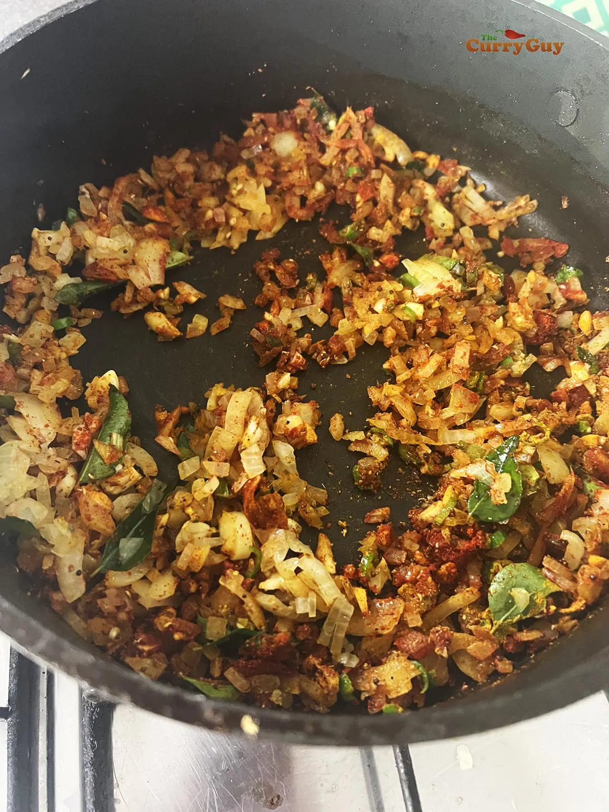 Frying onions, chillies and ground spices in a pan.