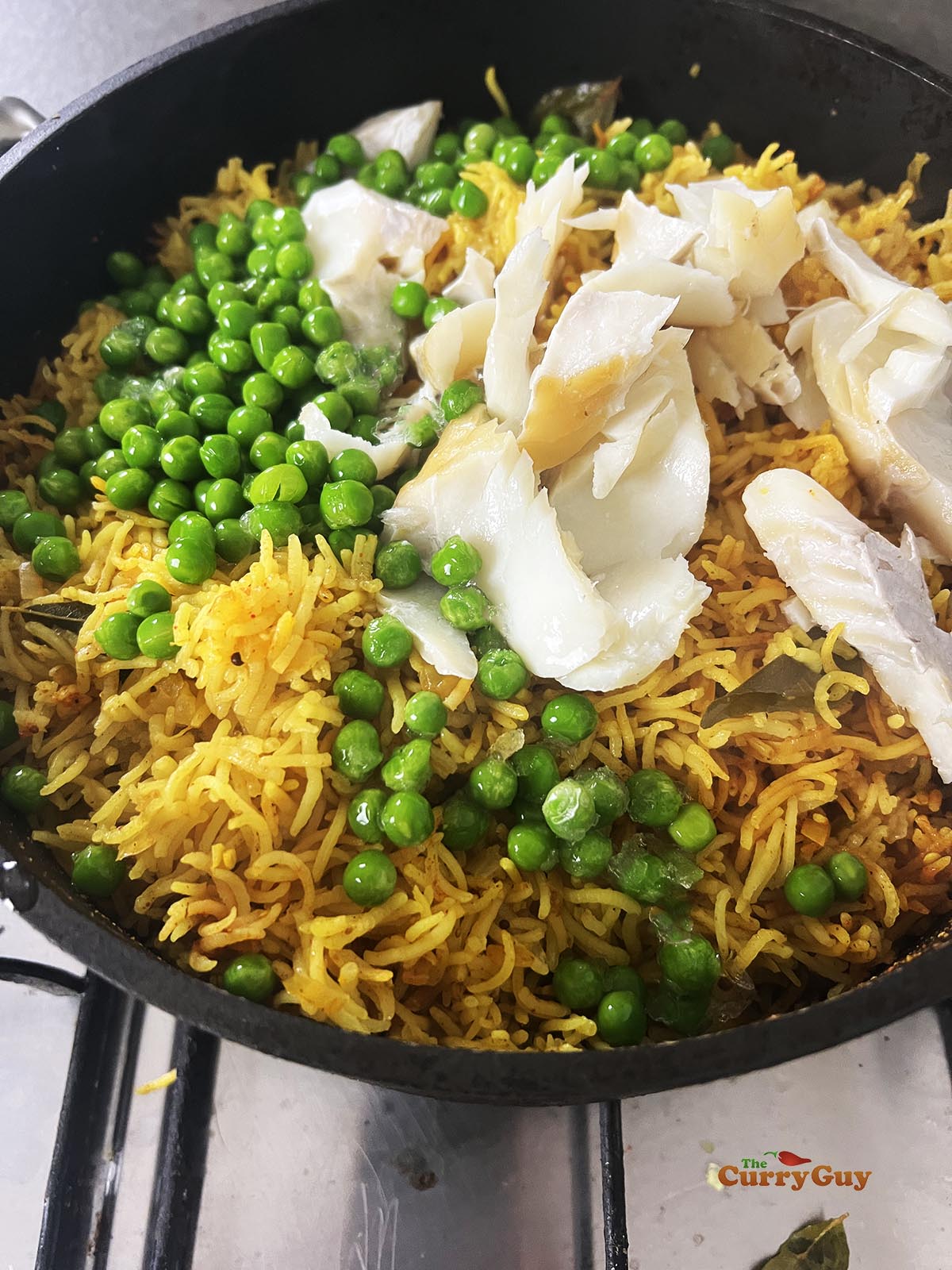Adding the smoked haddock and peas to the rice.