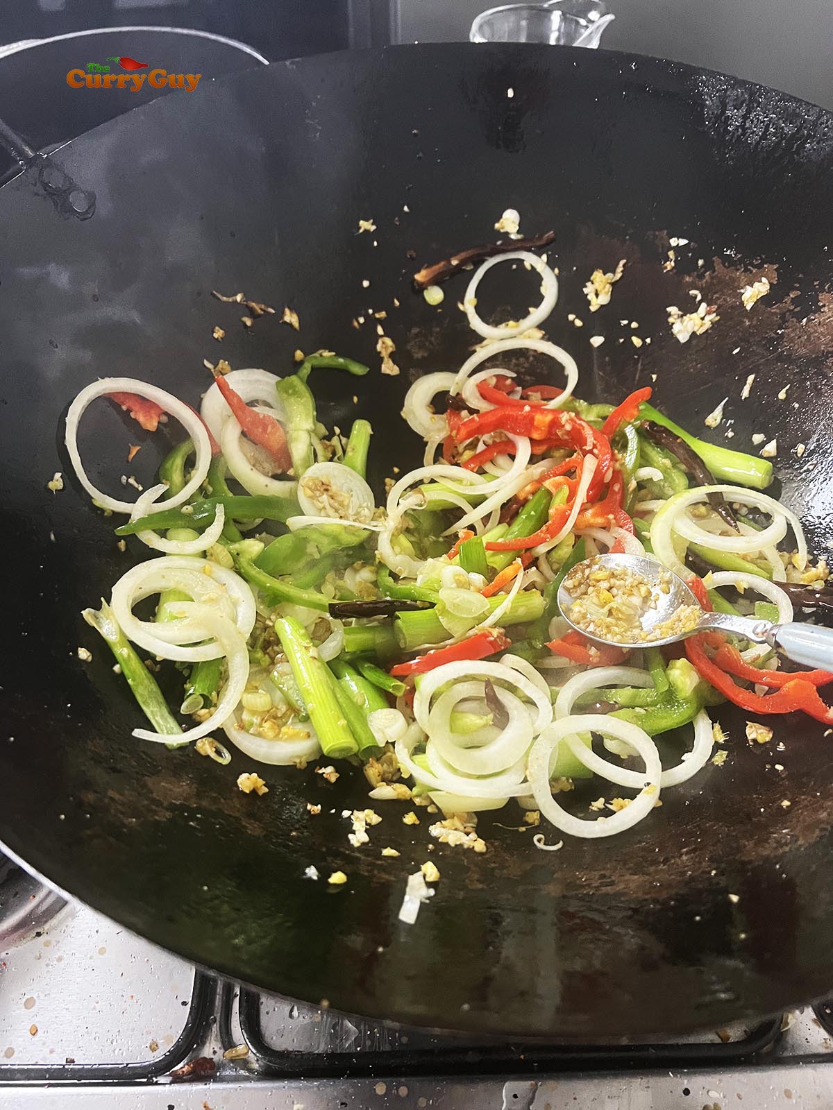 Adding the onions and bell peppers to the wok.