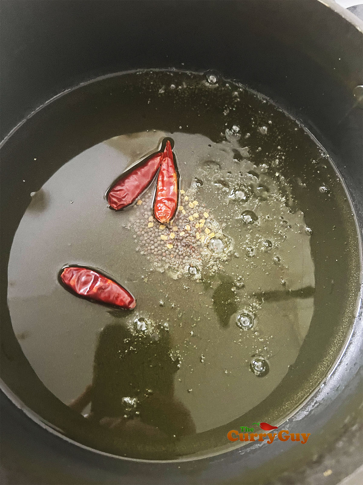 Adding dried chillies to the oil.