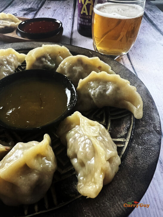 Beef momos served on a plate with a dipping sauce.