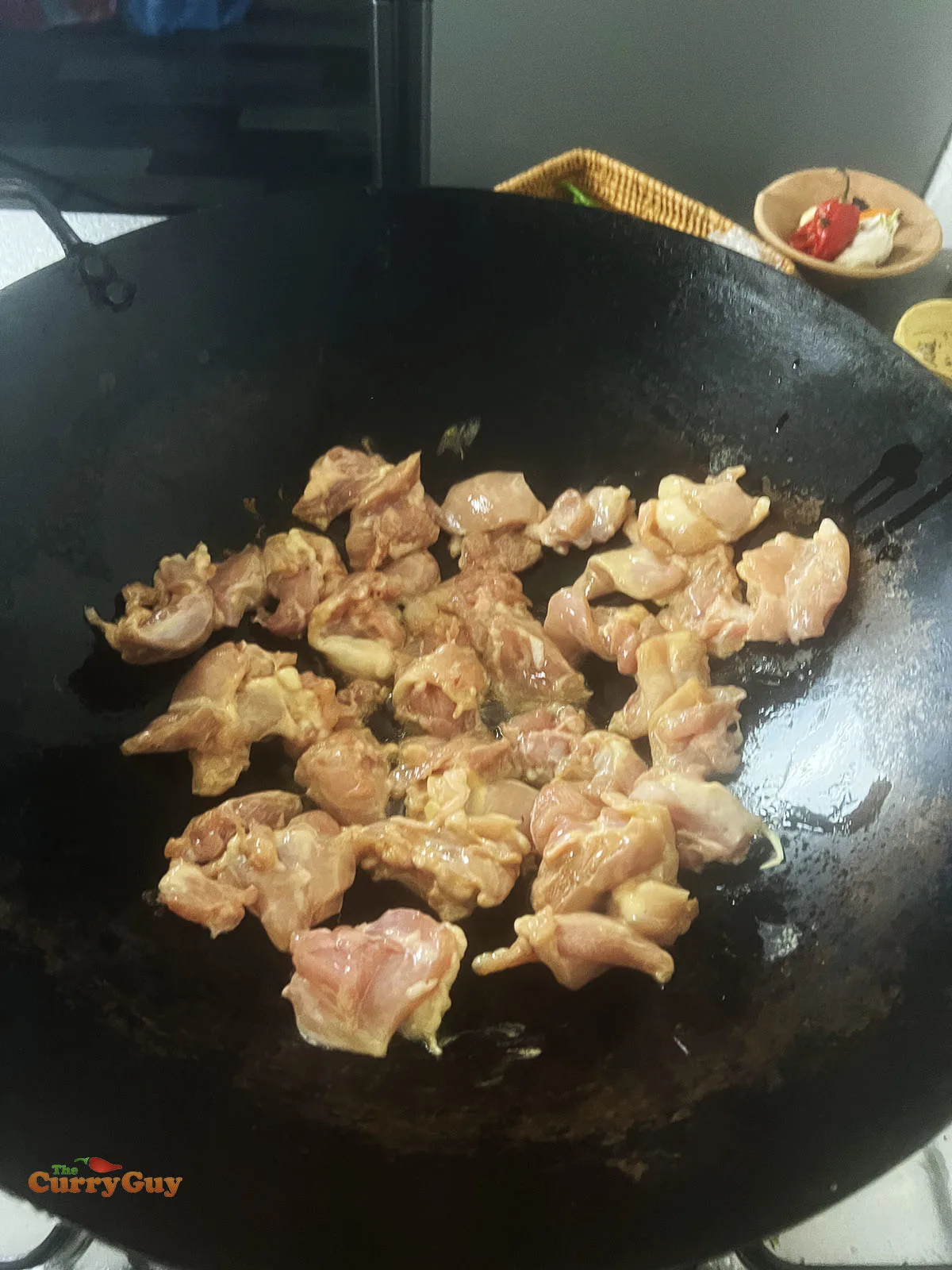 Frying the marinated chicken in a hot wok.