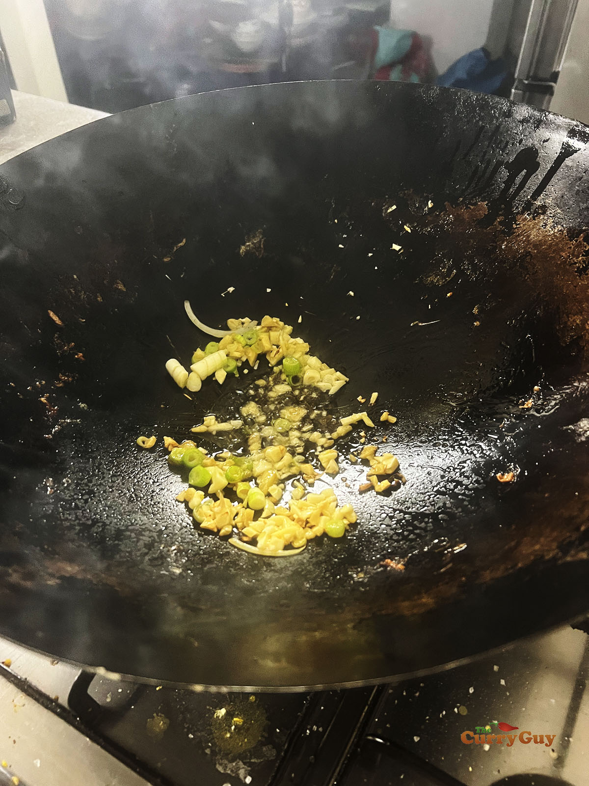 Frying the aromatic ingredients, ginger, garlic and spring onions (scallions)