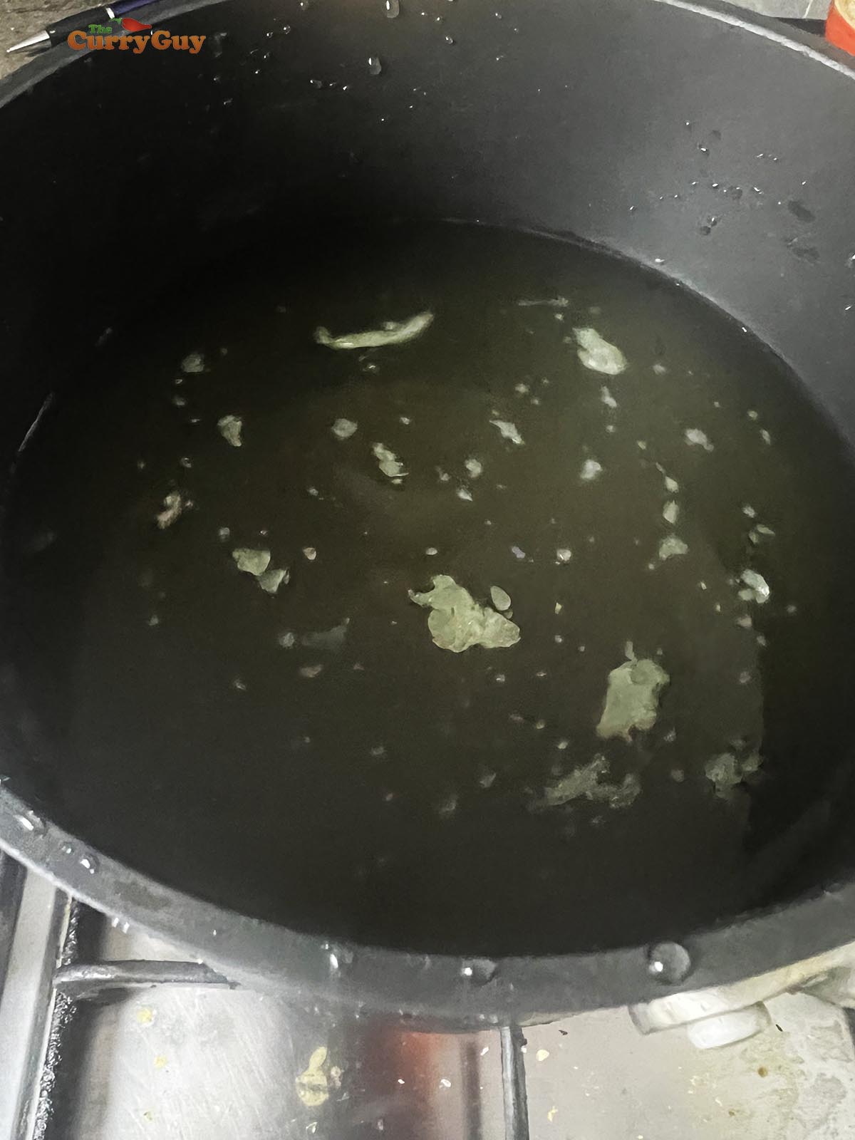 Bringing the chicken stock to a simmer in a saucepan.