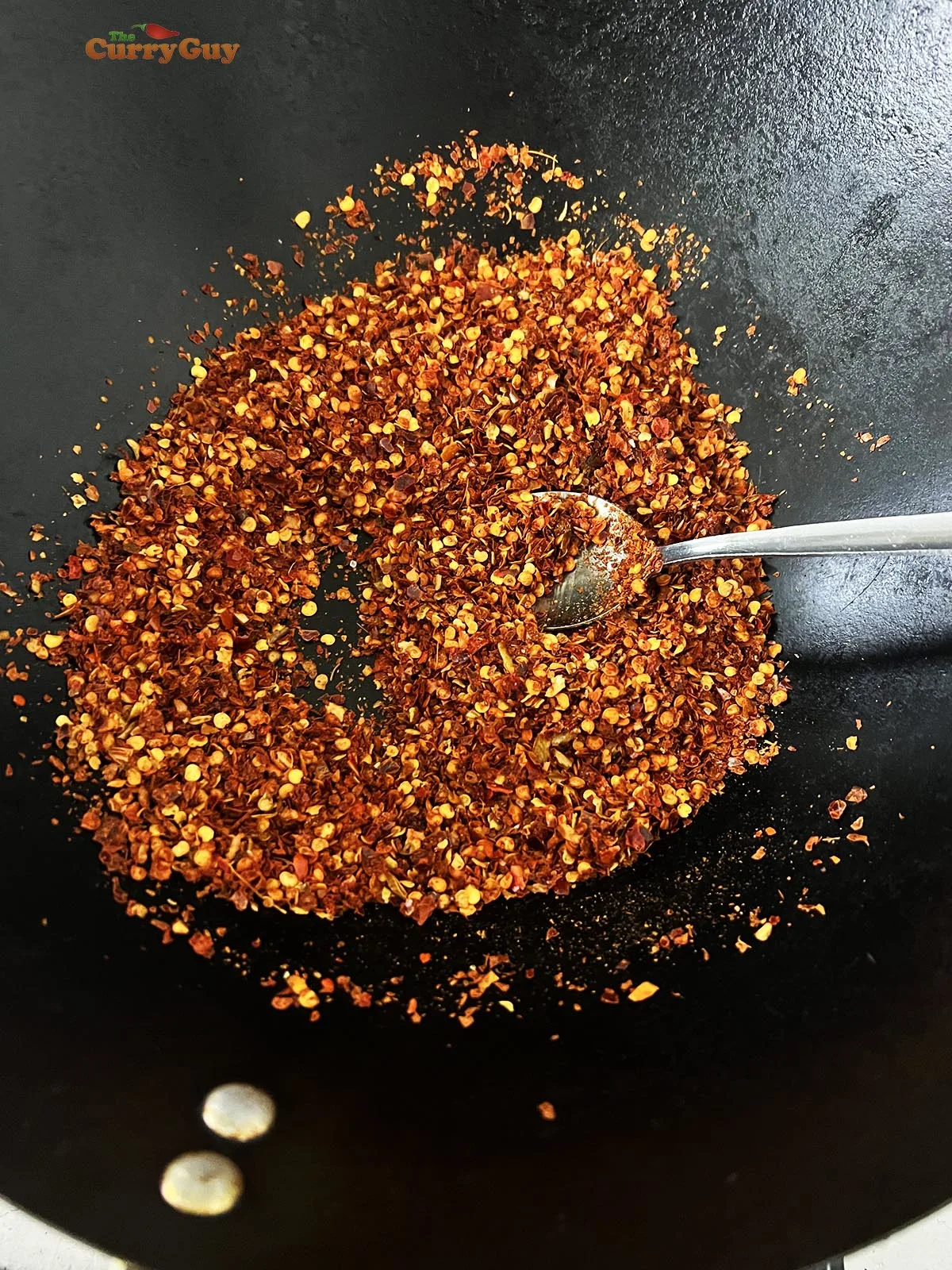 Toasting chili flakes in a wok.