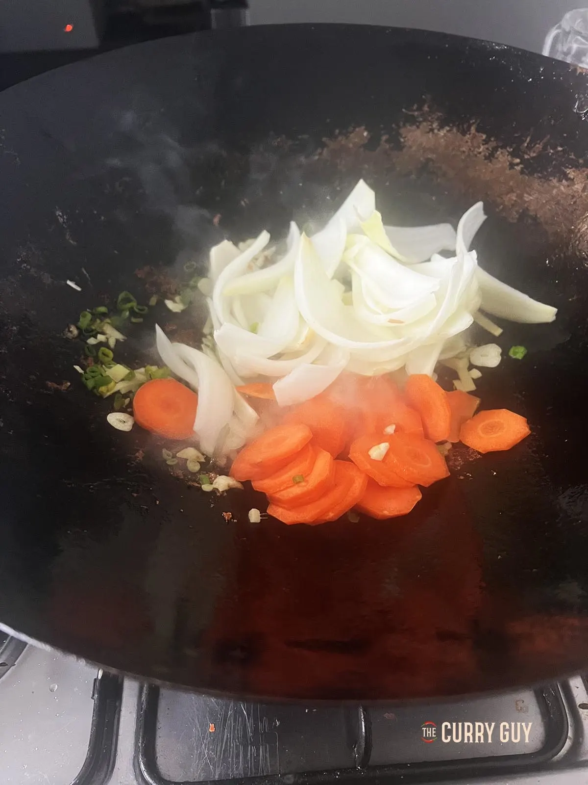 Adding and frying the sliced onions and carrots.