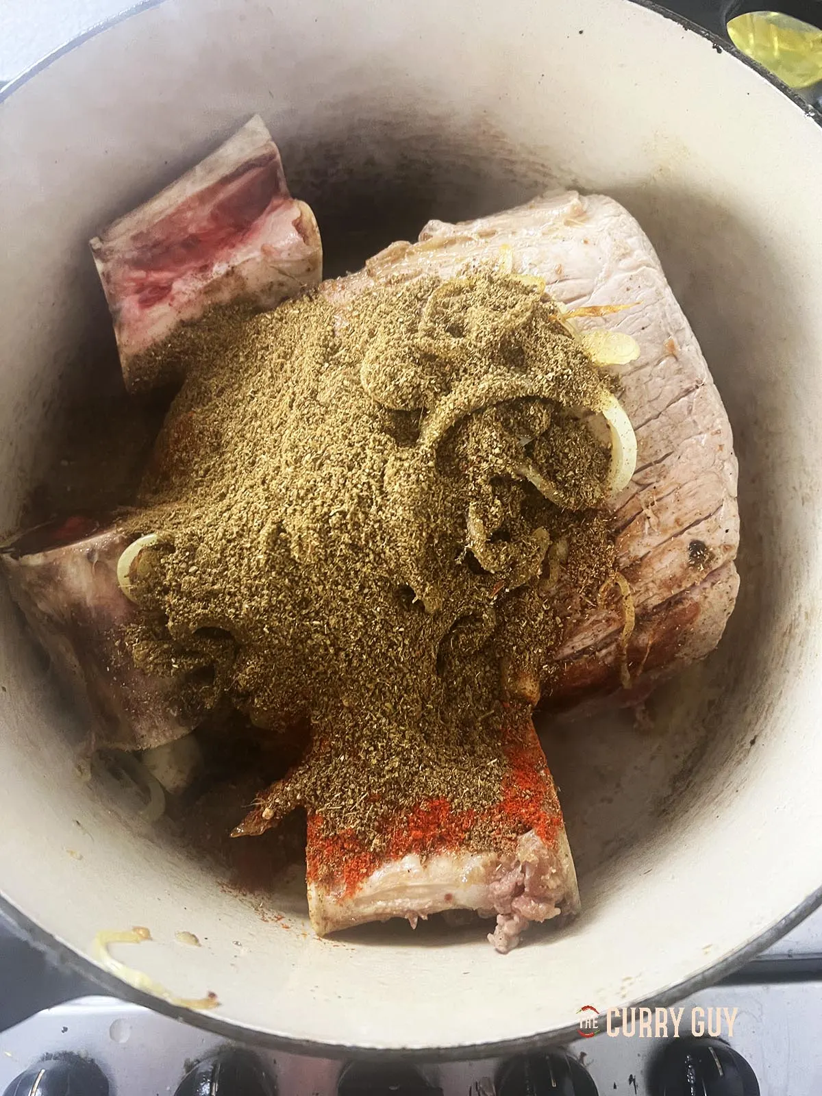 Adding the fried onions, garlic and marrow bones to the pot.