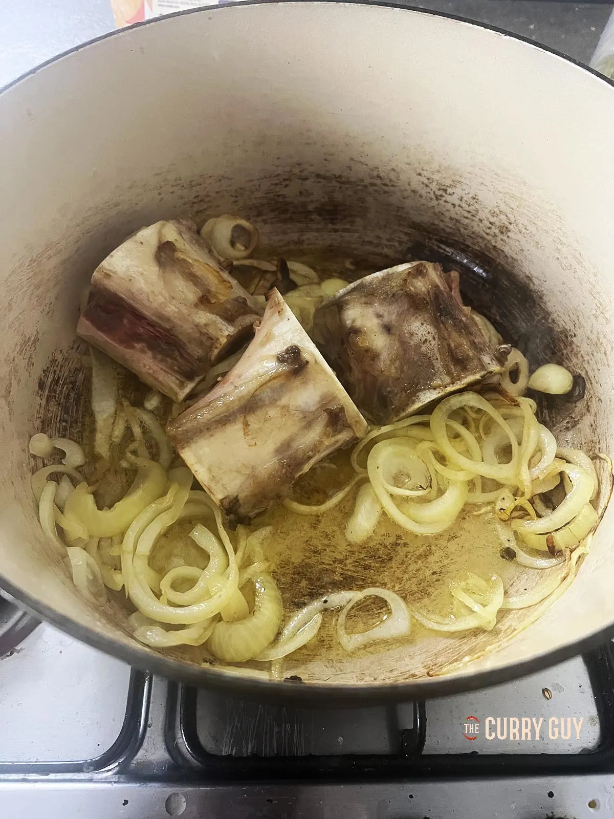 Frying the sliced onions, marrow bones and garlic in the pot.