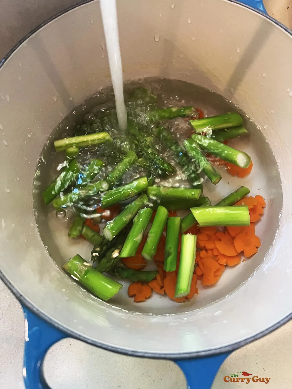 Running cold water of the strained asparagus and carrots.
