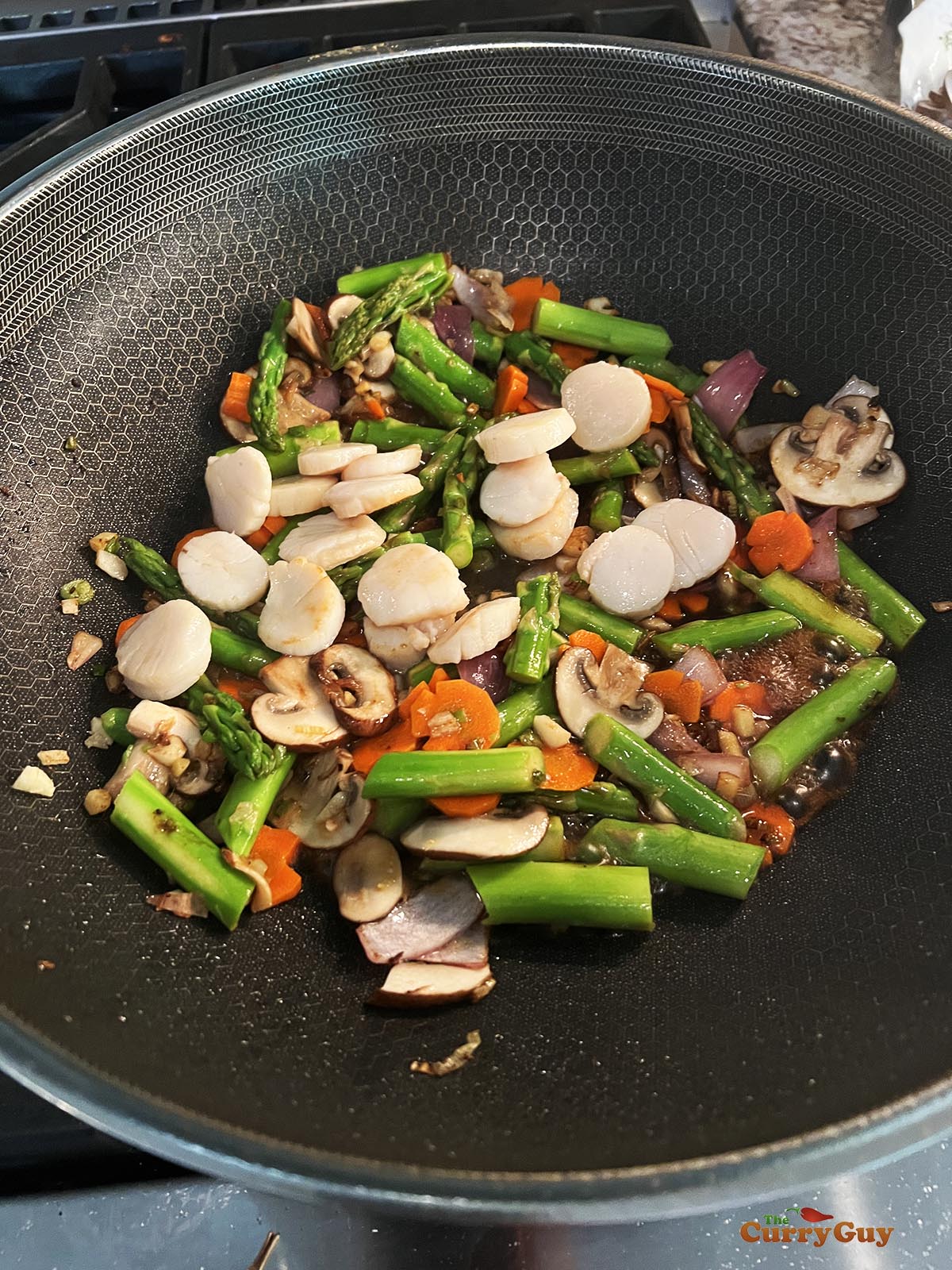 Adding the seared scallops to the wok.