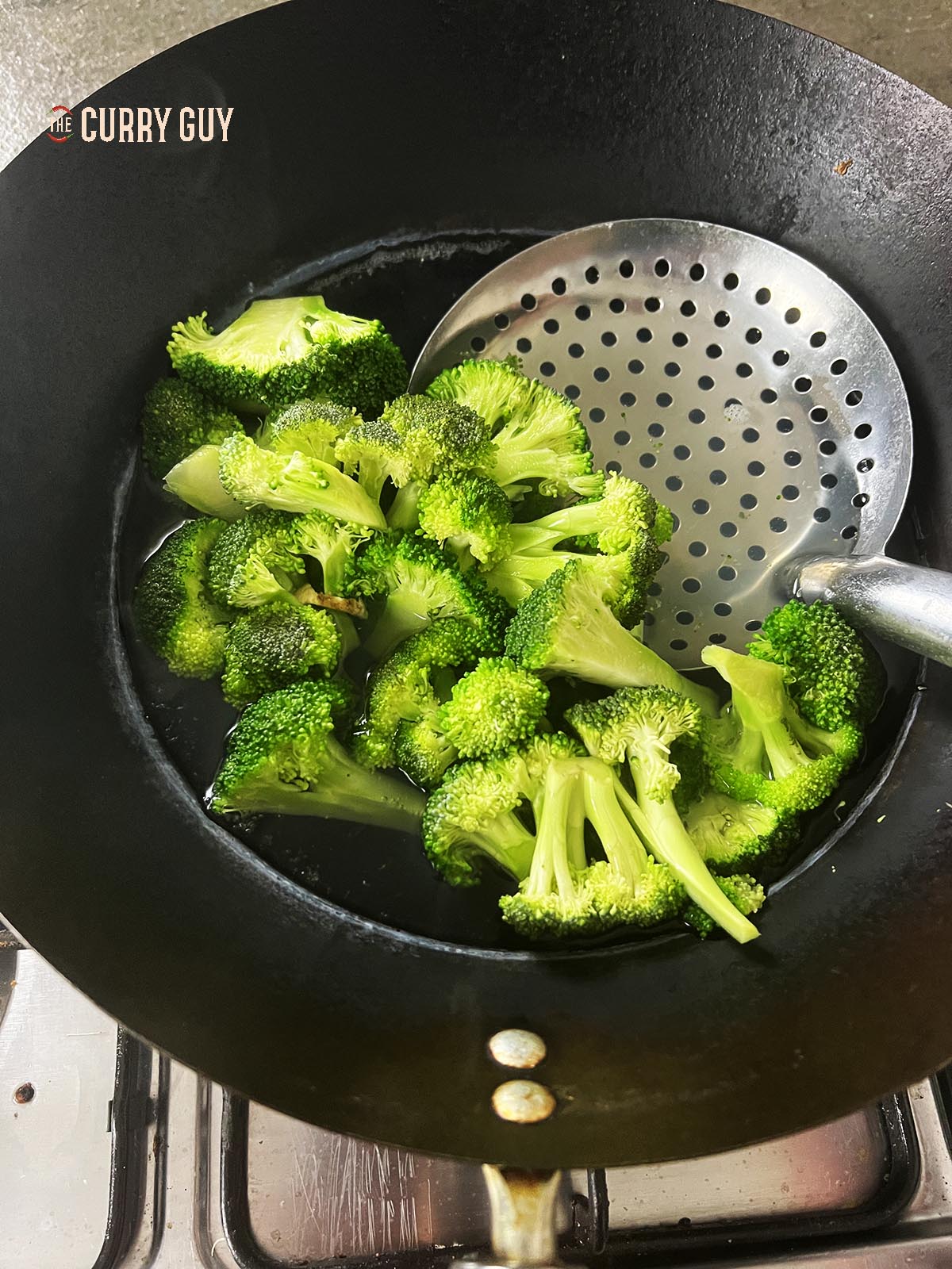 Blanching the broccoli in a wok.