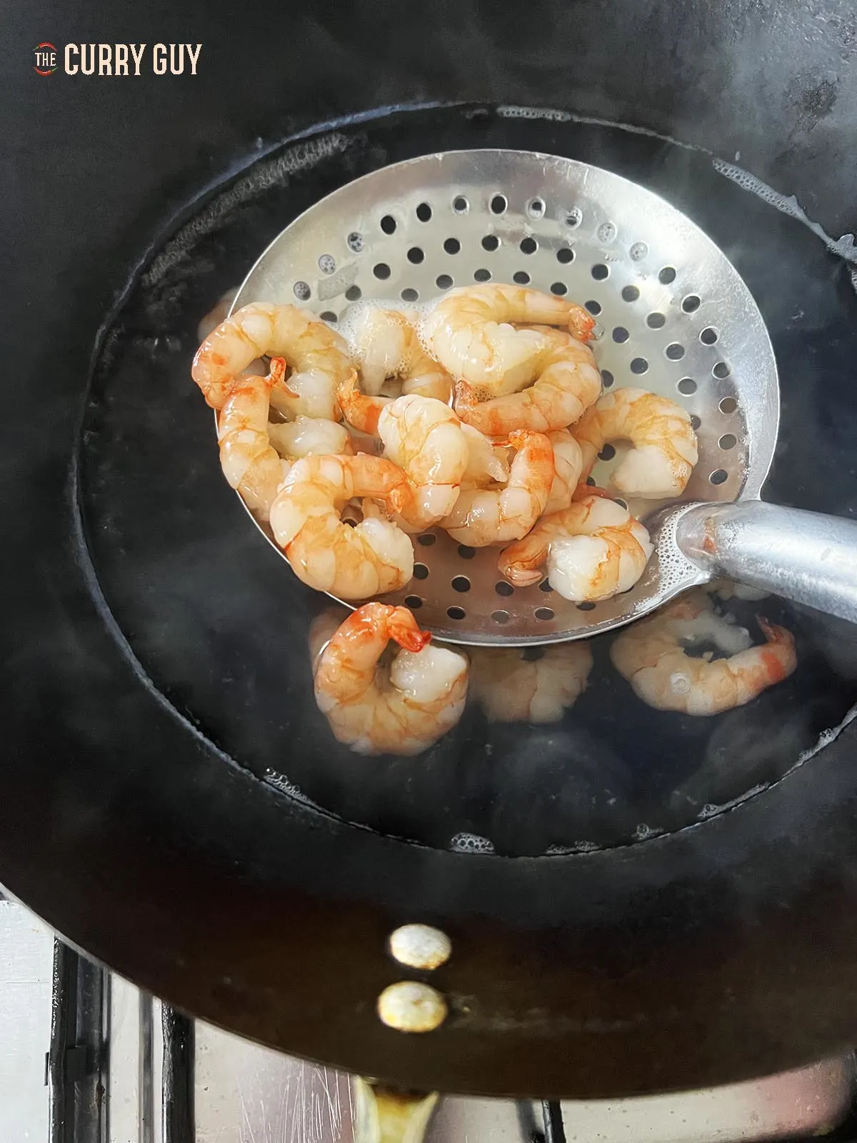Blanching the shrimp in a wok.