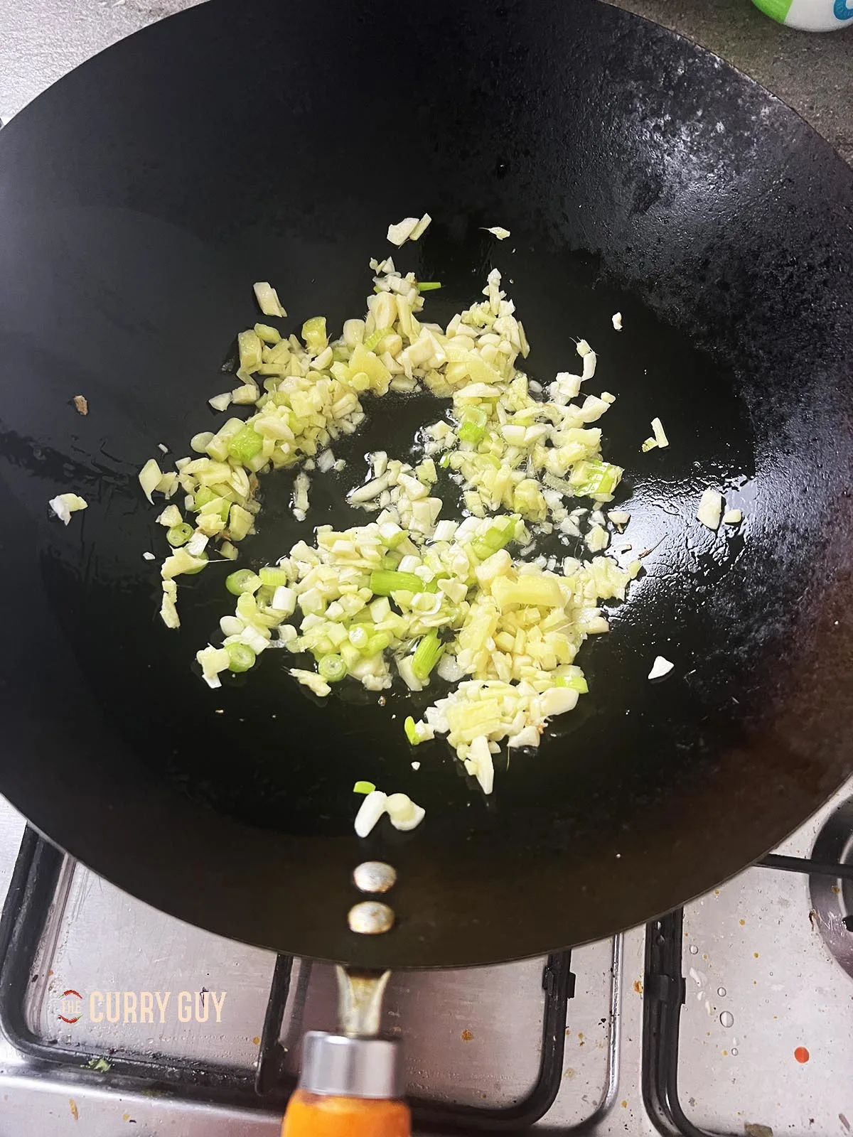 Frying garlic, ginger and spring onions (scallions) in a wok.