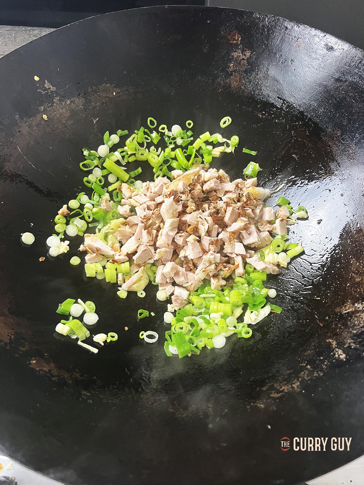 Adding and frying diced chashu pork to the wok.