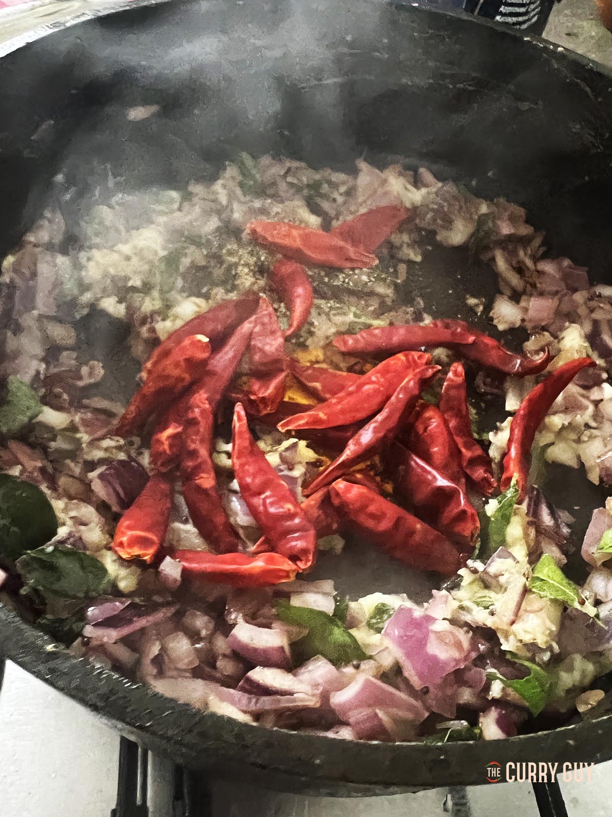 Adding the ground spices and rehydrated, dried chillies to the pan.