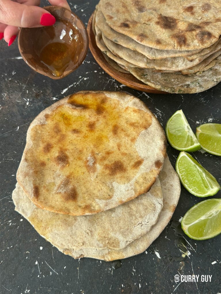 Tandoori rotis on a countertop, drizzled with ghee.