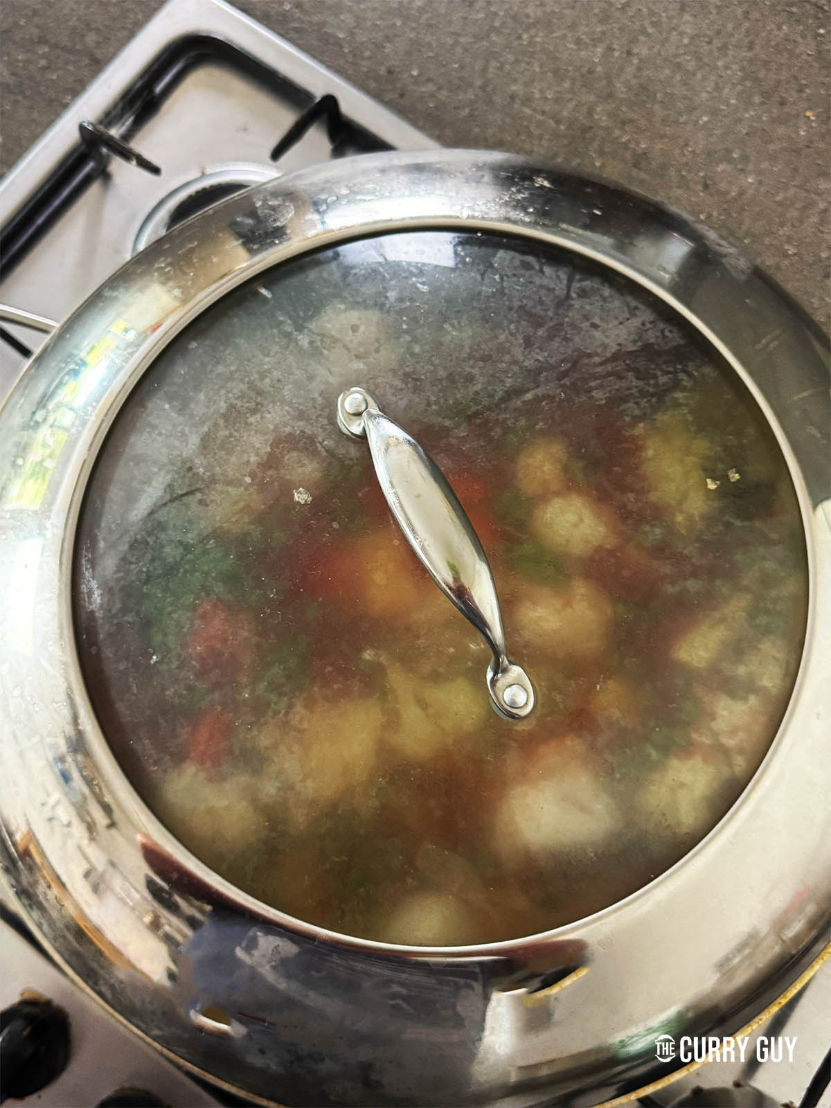 Covering the pot with the vegetables and water in it to simmer and cook.