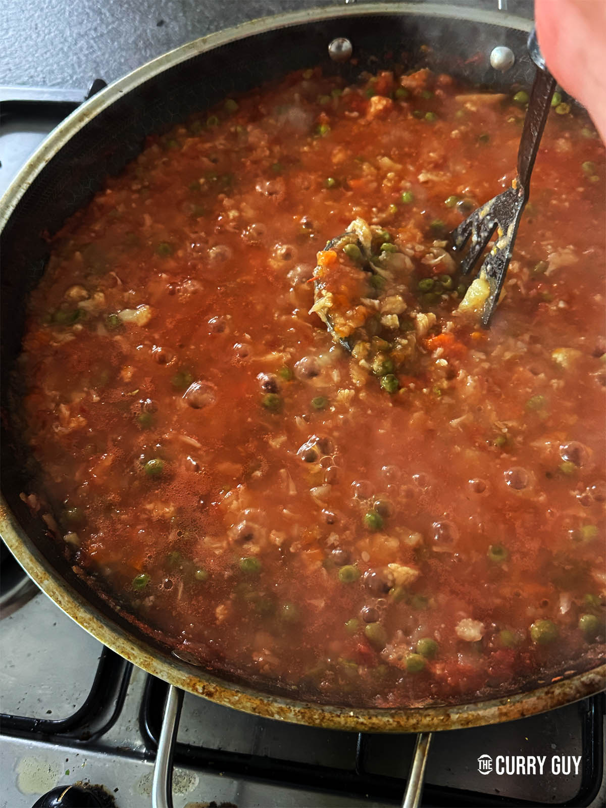 Mashing the vegetables with a potato masher.