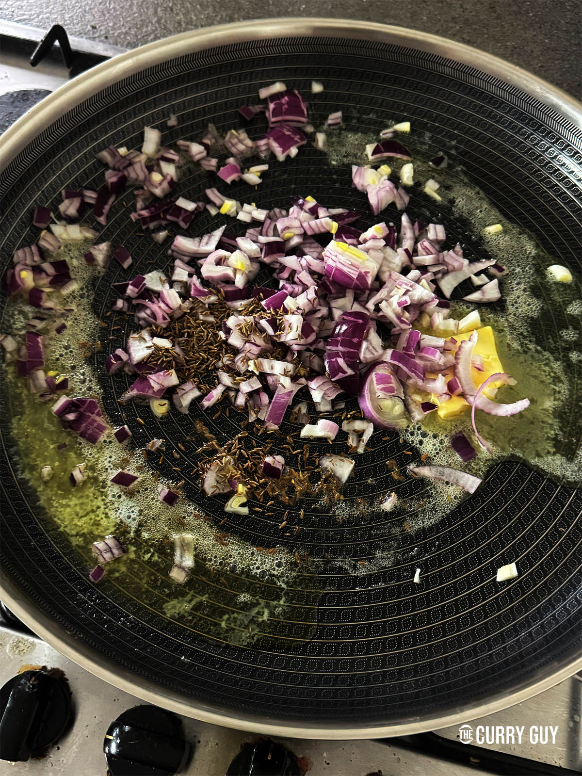 Frying the onions with the cumin seeds in butter in another pan.