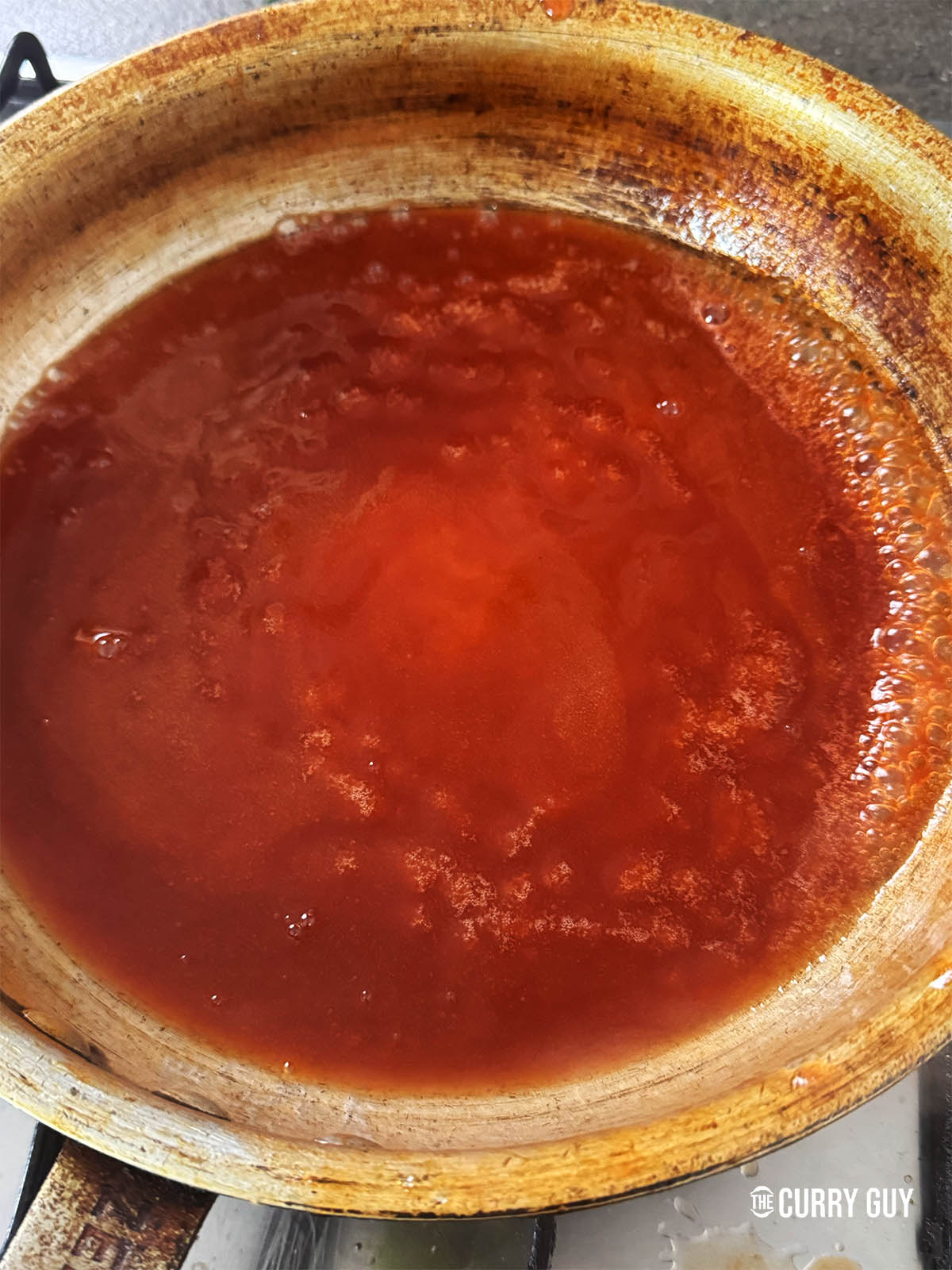 Adding the ketchup, orange juice, vinegar and food colouring to the pan.