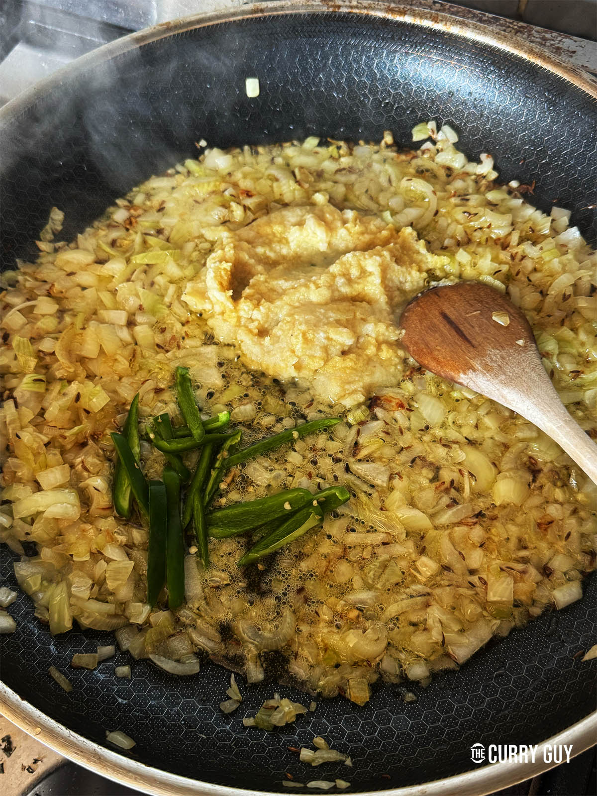 Frying the onions, garlic and ginger paste and the chillies in the pan.