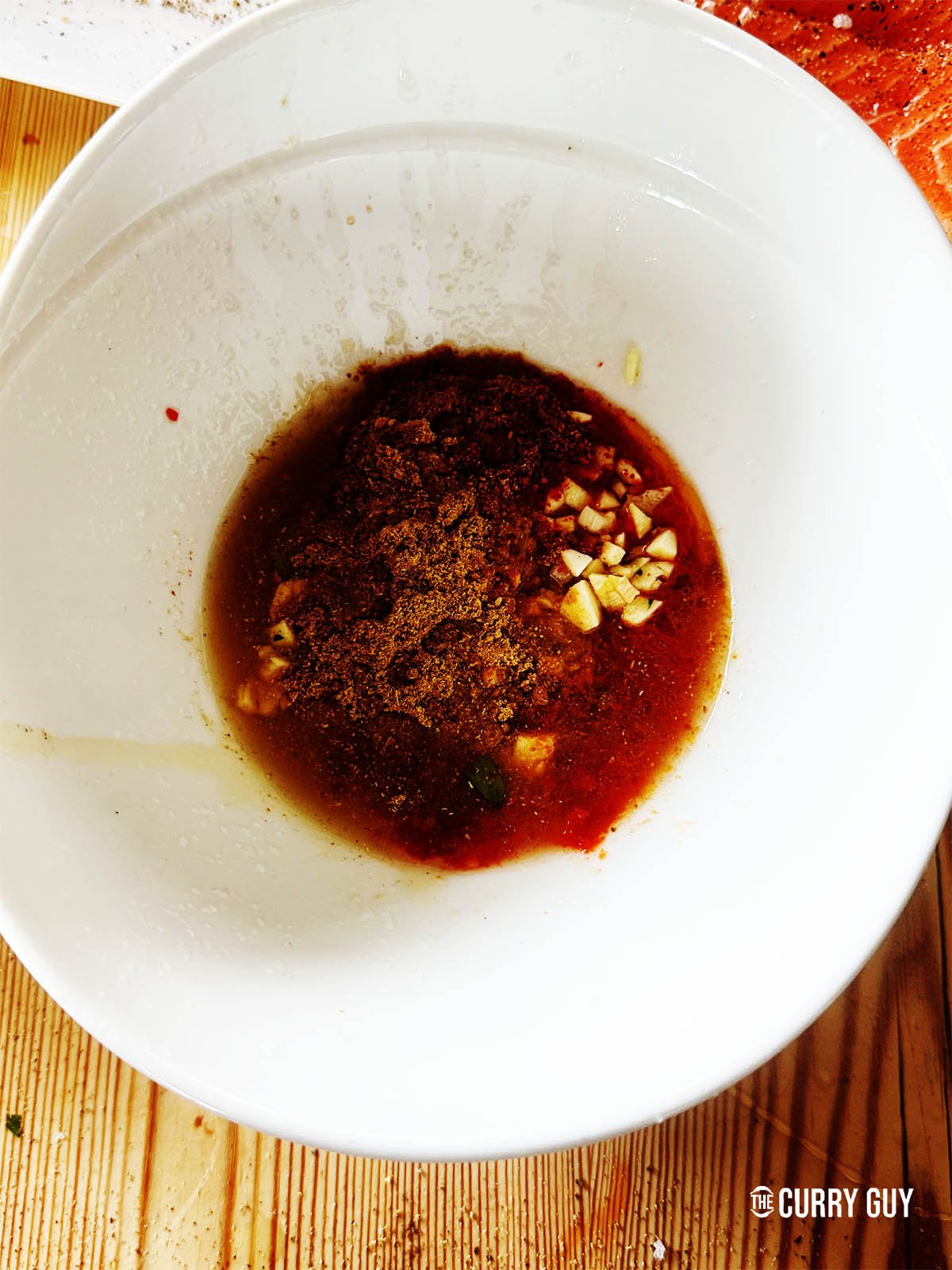 La pâte de harissa dans un bol avec l'ail, l'huile d'olive, le miel, le jus de lime, le piment Aleppo, la coriandre, le cumin et le gingembre moulu.