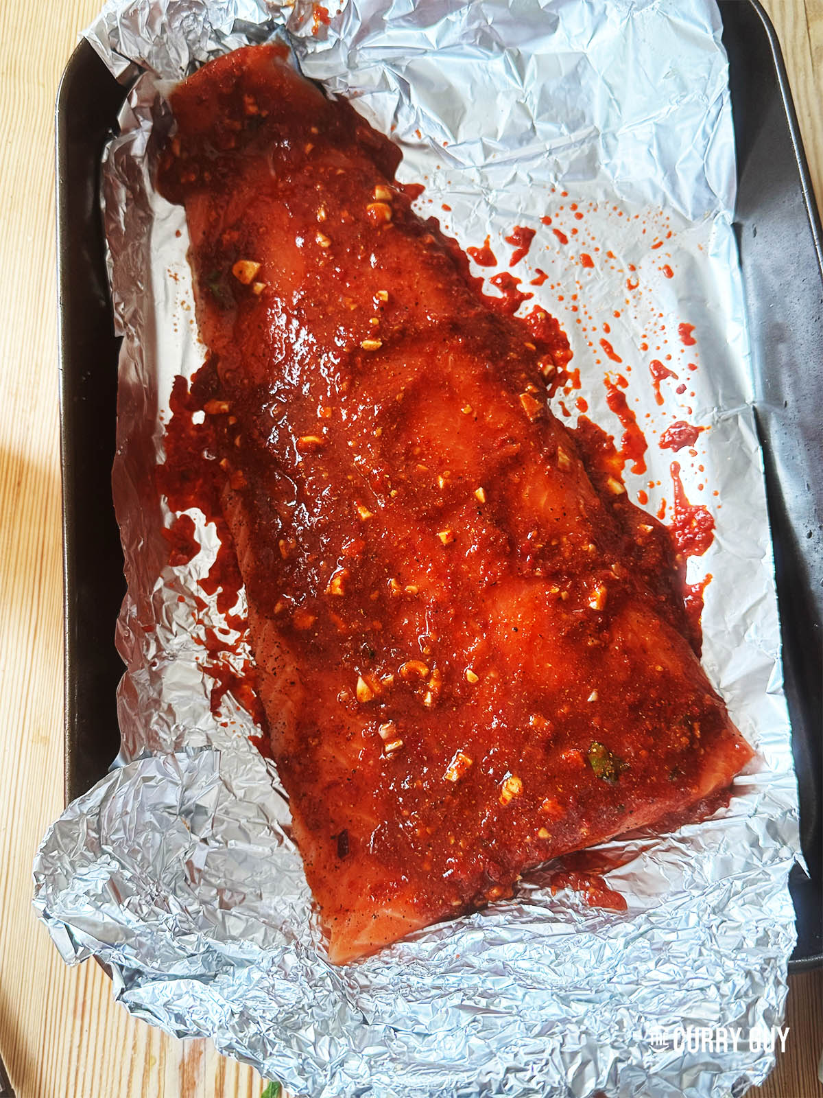 Étalez la pâte de harissa sous et sur le saumon sur le papier aluminium.