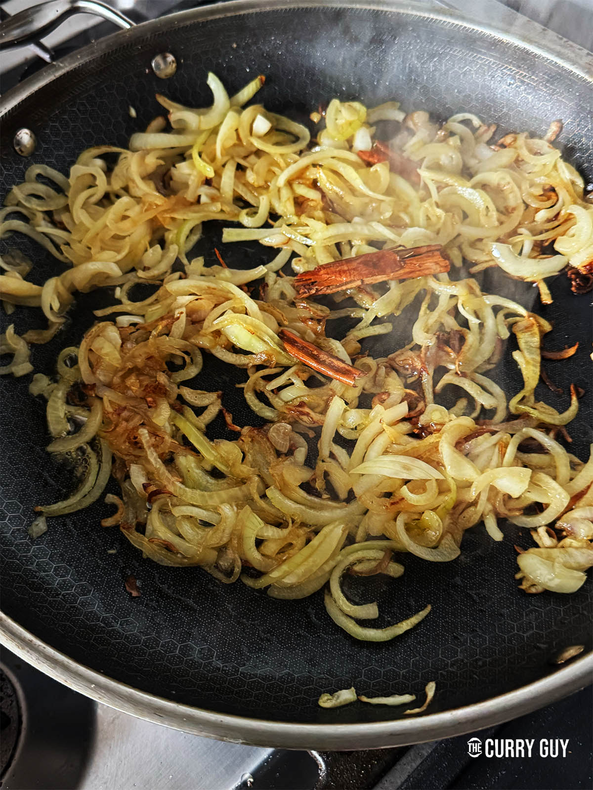 Frying the onion with the cinnamon stick until browned.