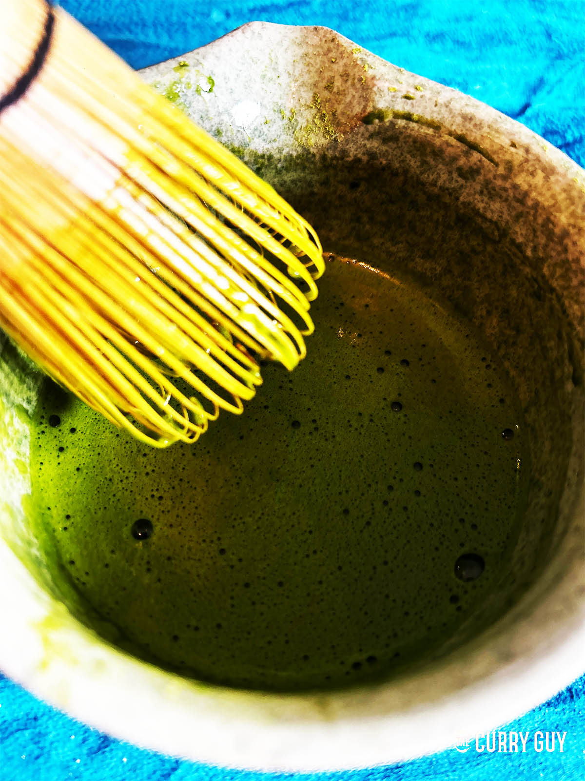Adding the remaining water to the matcha and whisking until smooth. 
