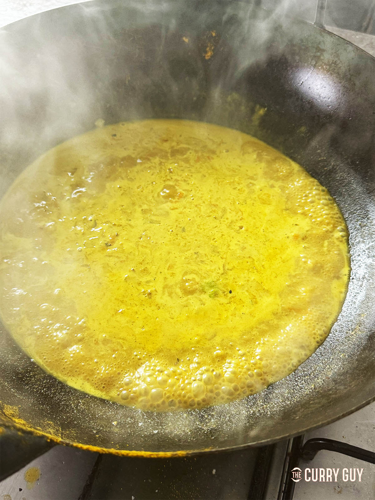 Adding soy sauce and honey to the sauce in the wok. 