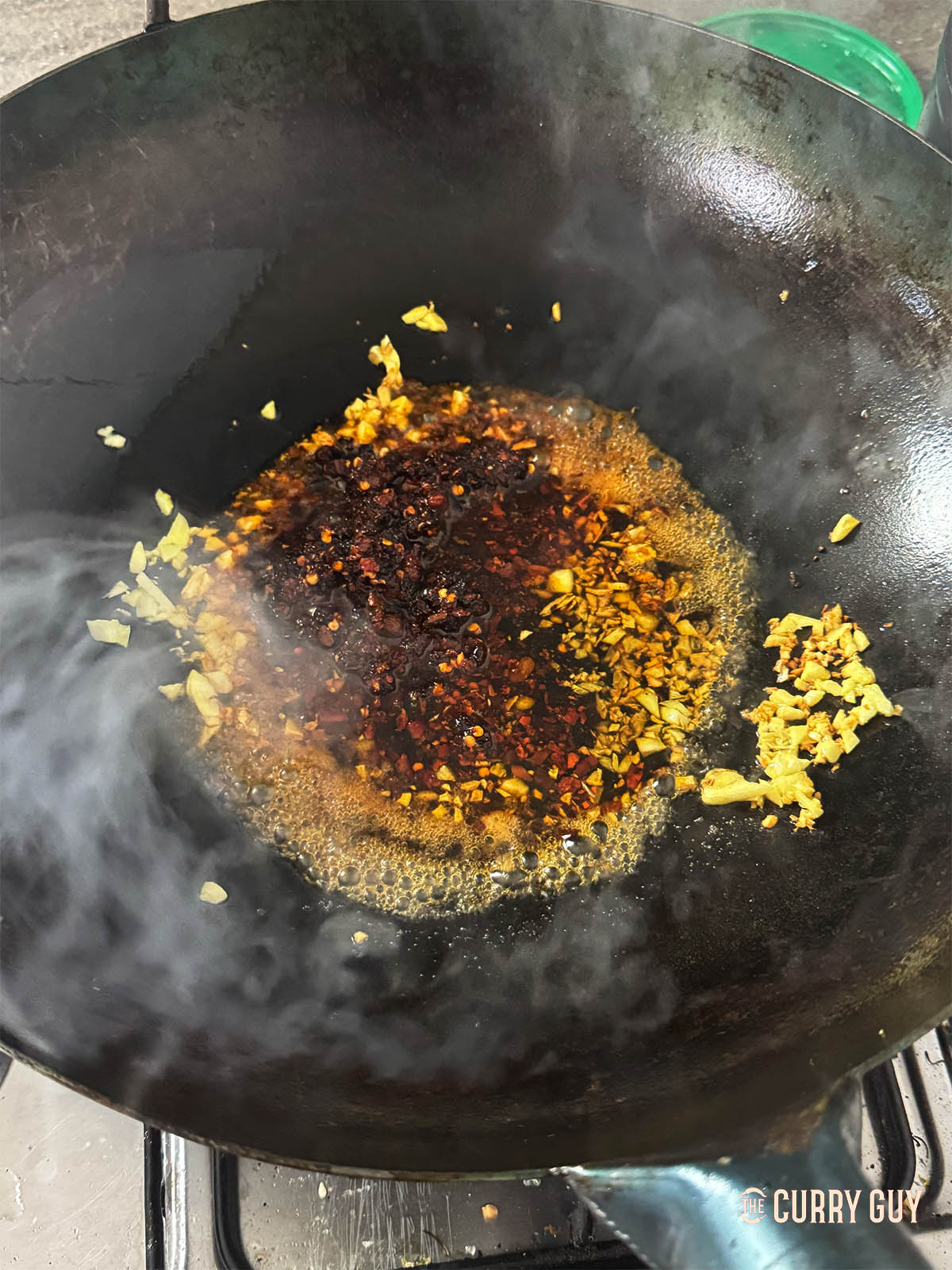 Adding the sesame oil, mirin, Chinese crispy chilli and soy sauce to the wok.