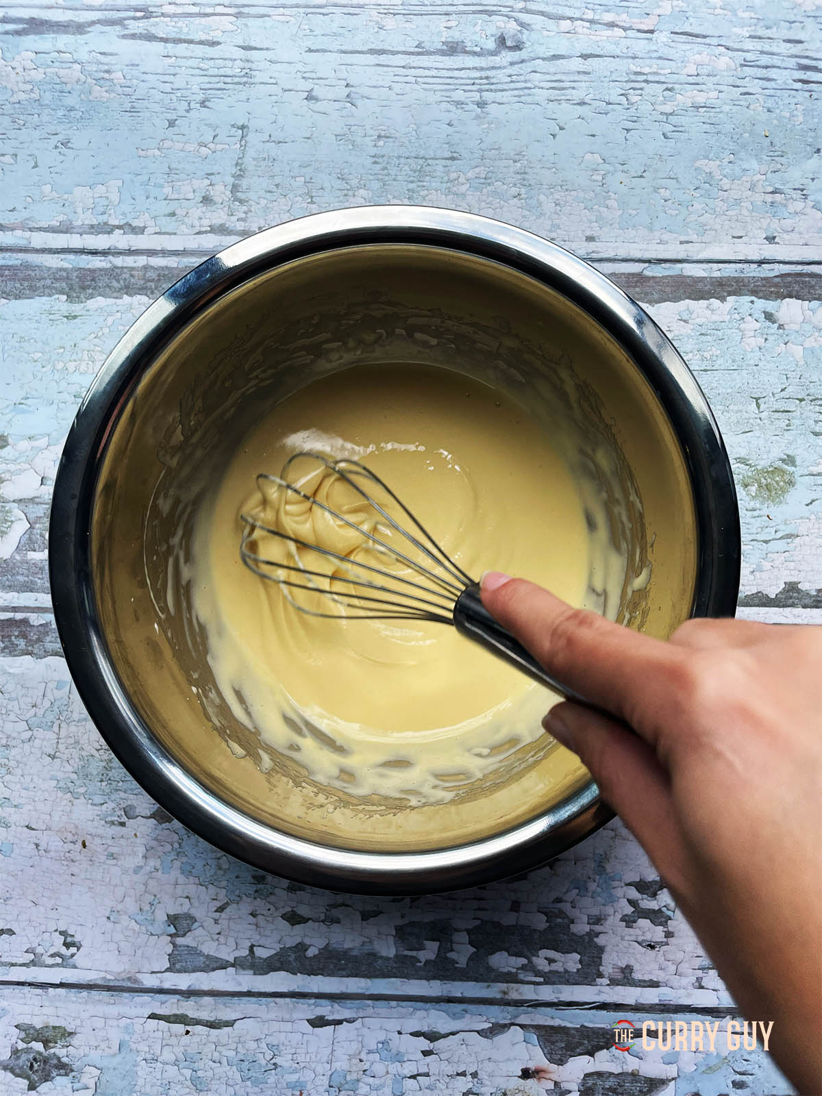 Whisking the egg yolks, condensed milk and vanilla extract together until thick and creamy.