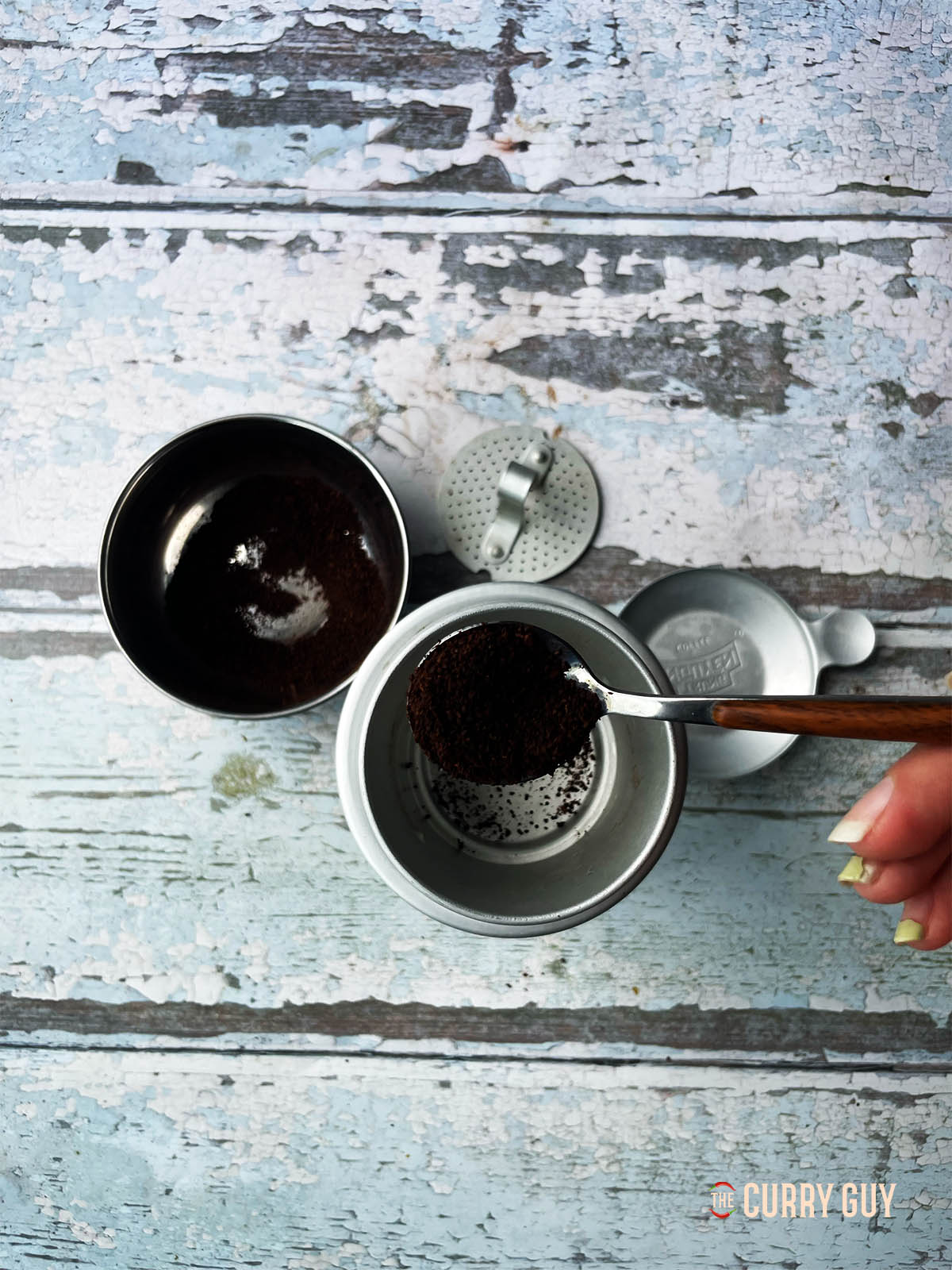 Adding coffee to a phin filter for brewing the coffee.