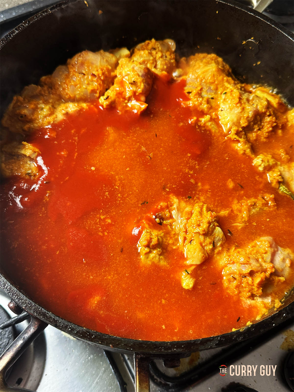 Ajout de la passata et du bouillon de poulet à la poêle pour porter à ébullition et cuire le poulet.
