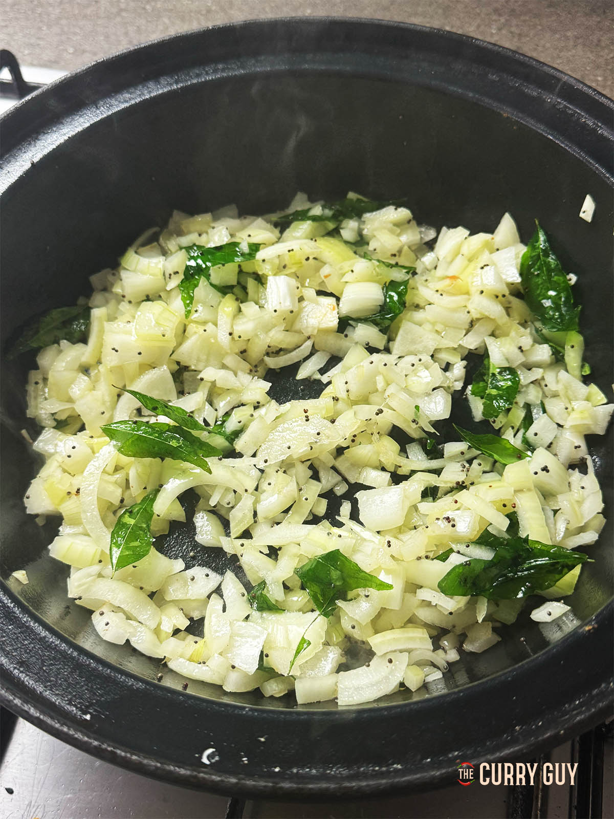 The onions frying in the pan with the curry leaves and mustard seeds. 