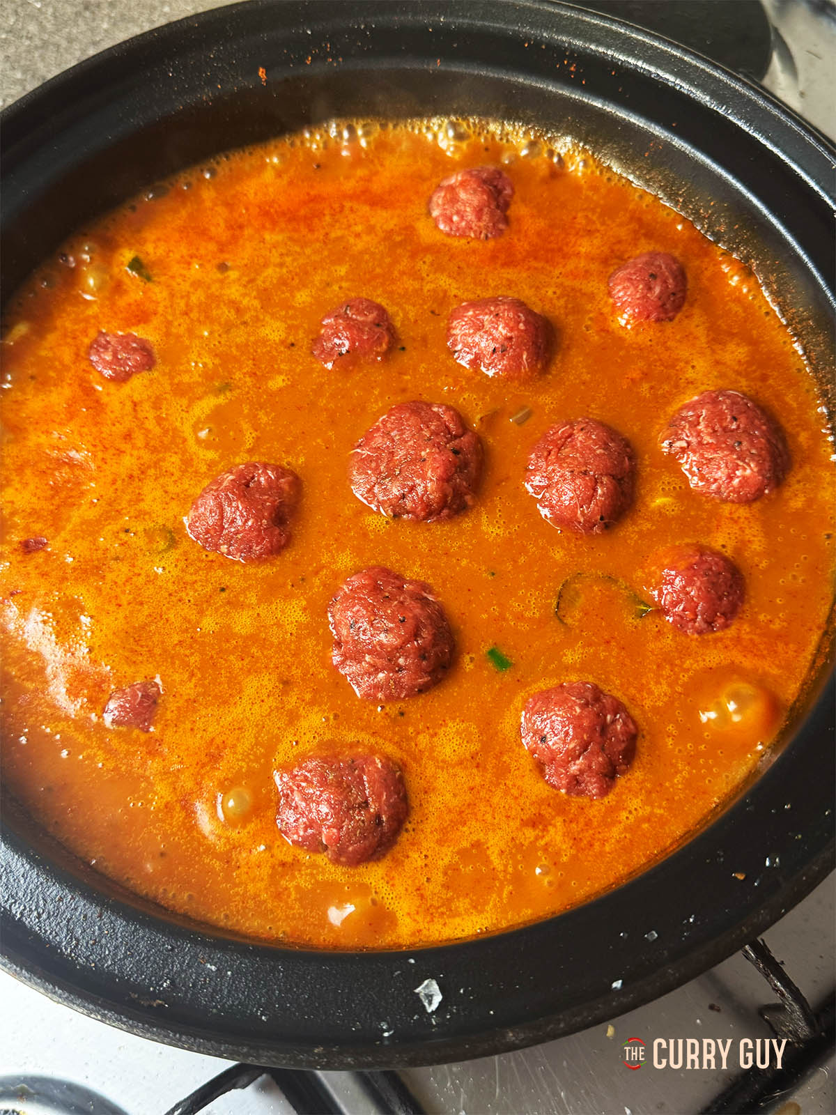 Adding the meat balls (kofta) to the pan.