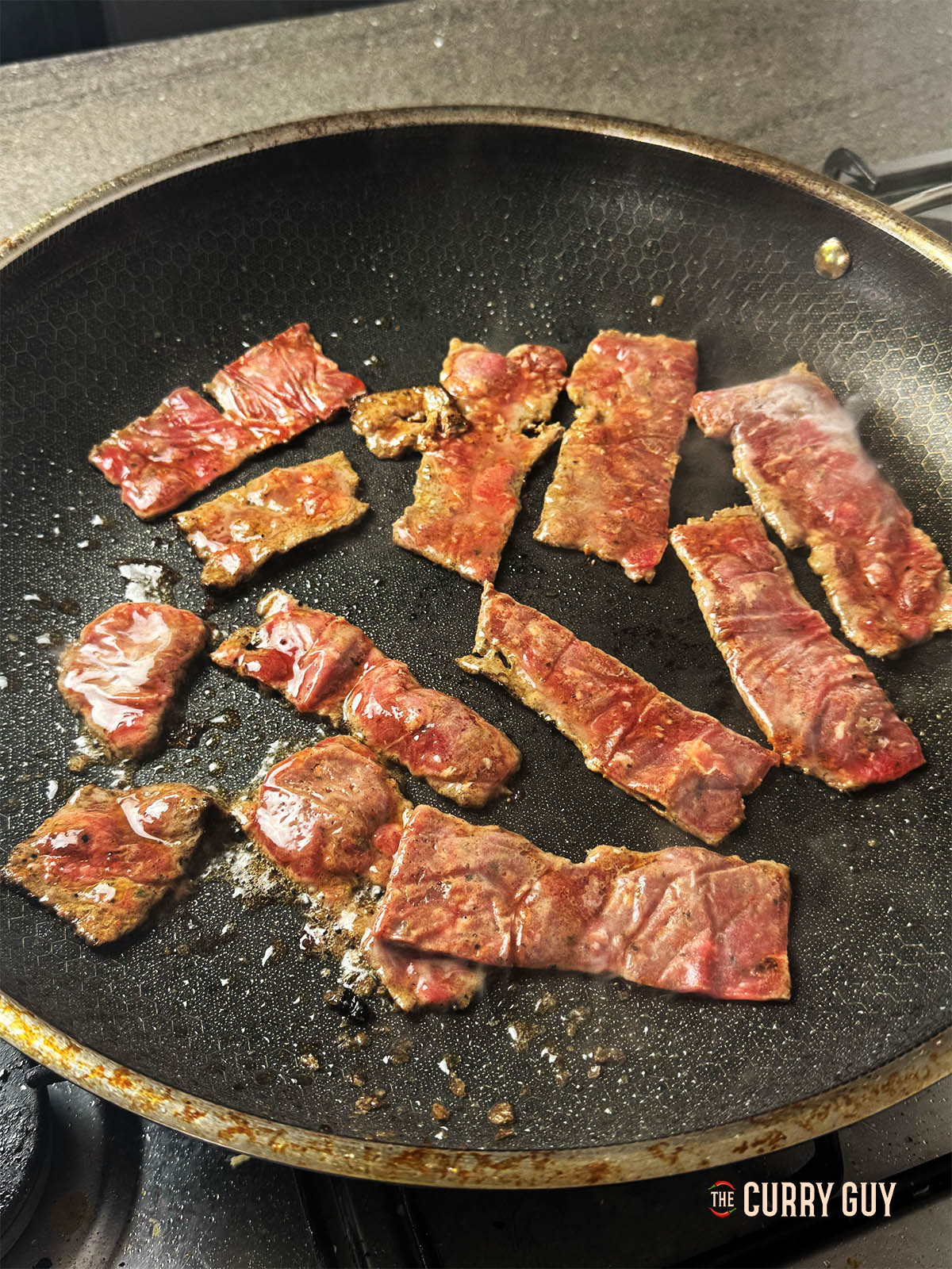 Frying the sliced meat in a pan.