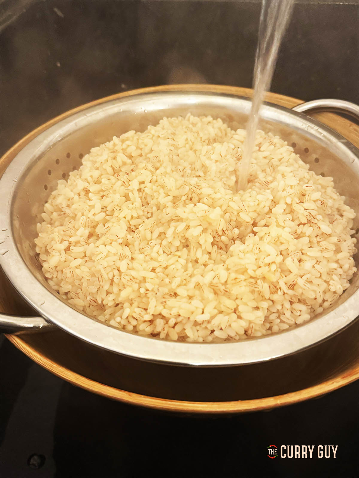 Filtrant le riz et courant d'eau sur celui-ci.