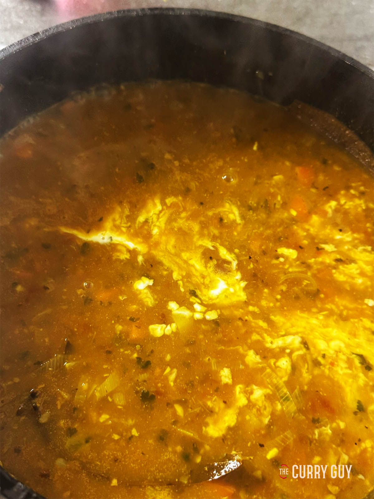 Adding coconut milk to the soup.