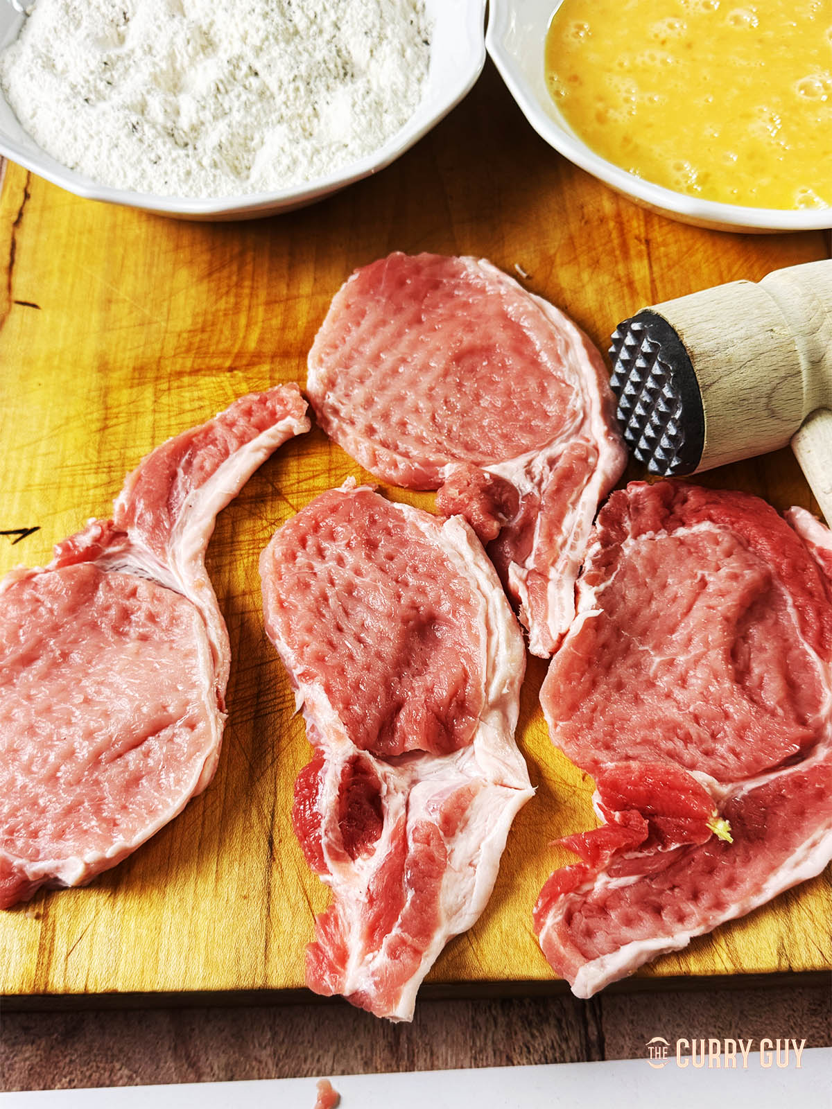 Using a meat mallet, pound the pork and tenderise the meat.