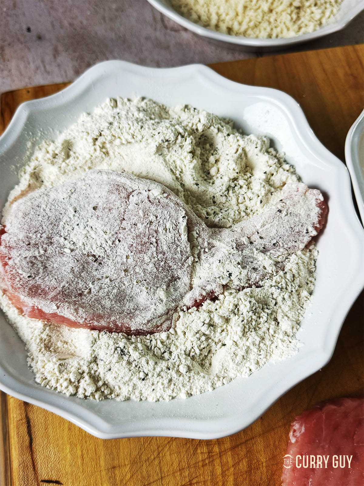 Dredging a pork loin chop in the flour, salt and pepper mixture.