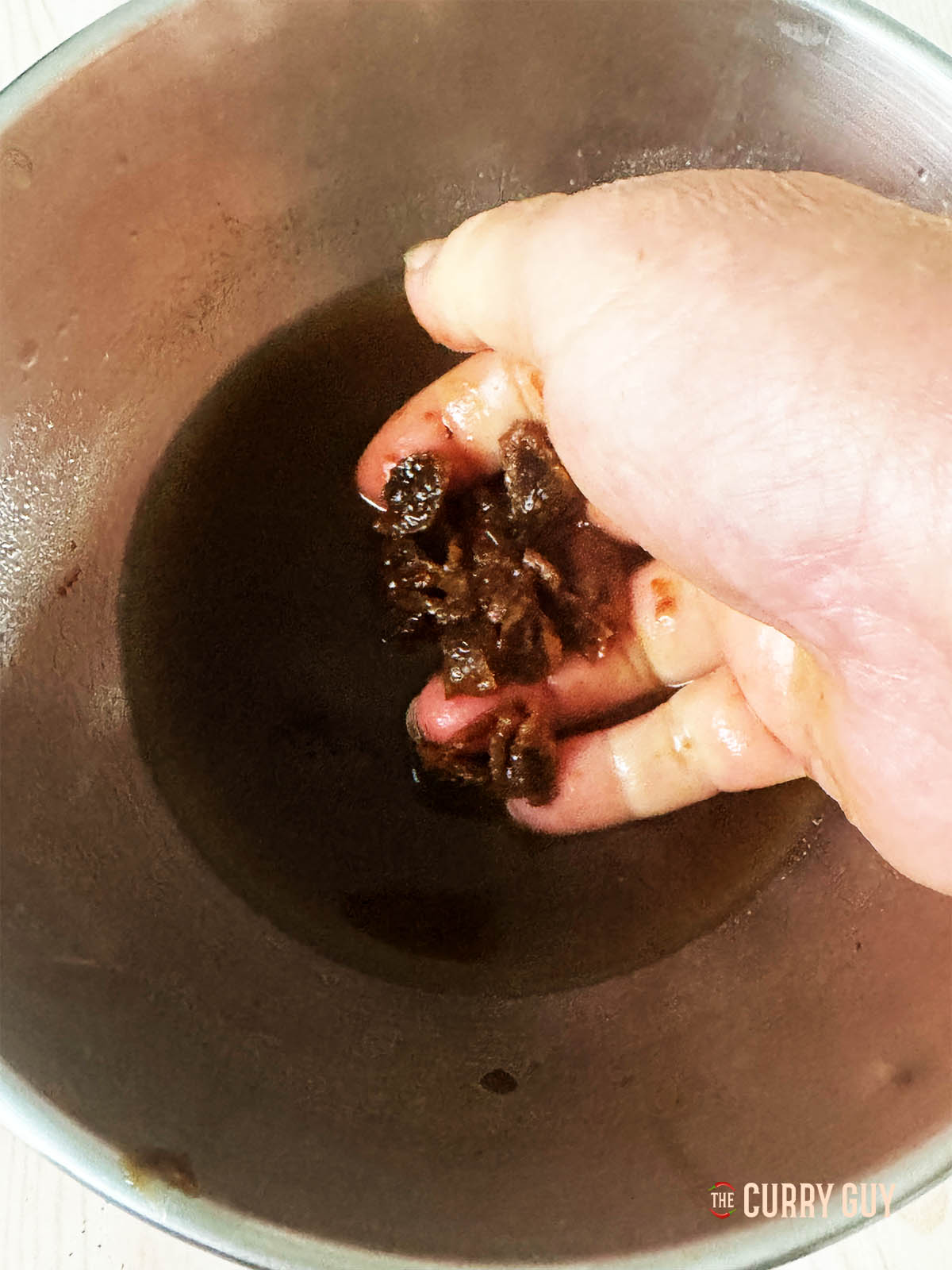 Breaking a ball of tamarind in a bowl of water.